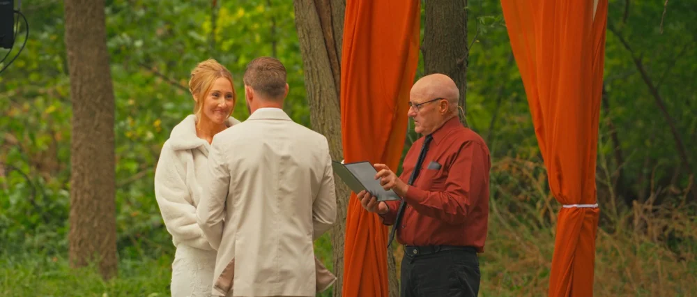 Abby smiling at Daniel during their outdoor wedding ceremony.