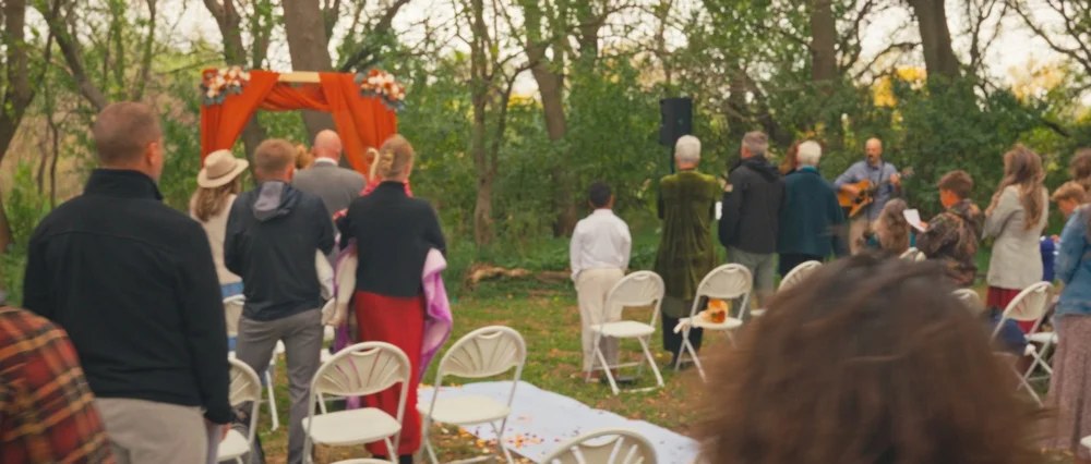 Family and friends standing among the trees at Abby and Daniel’s ceremony.