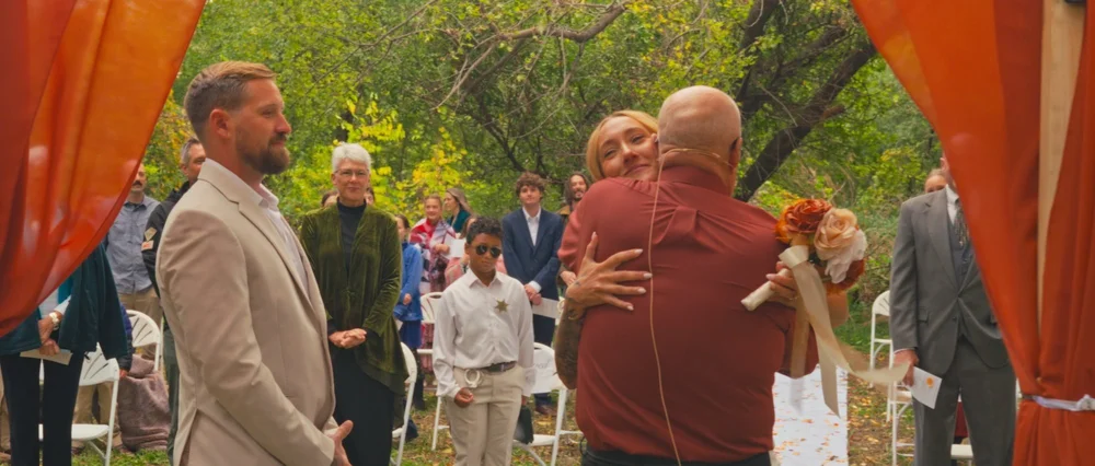 Abby embracing her dad as Daniel stands beside them at the ceremony.