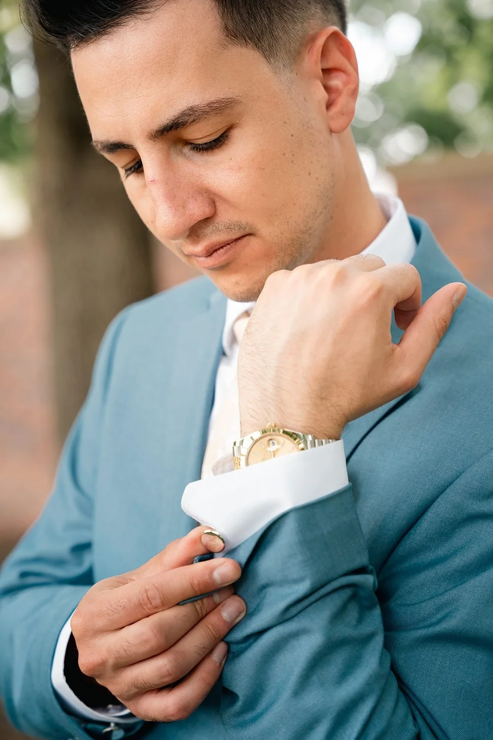 Alex adjusts his boutonniere during a groom portrait at the Ford Birthsite