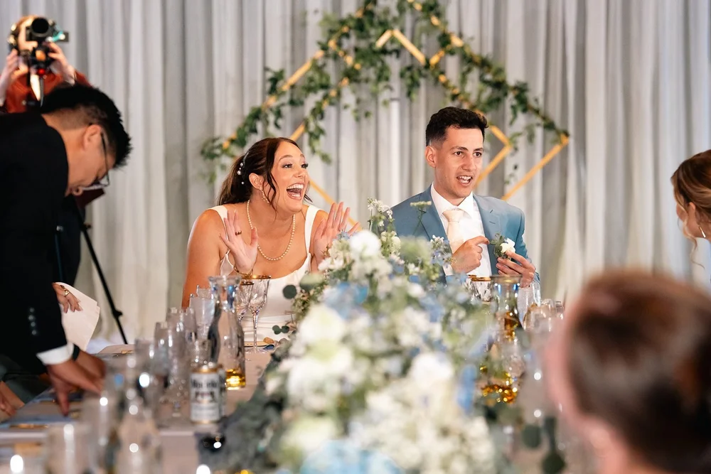 Grace and Alex laugh together while listening to speeches at their Omaha reception