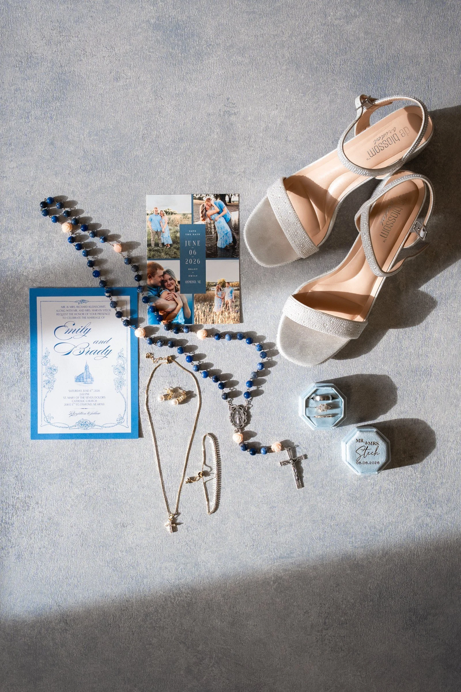 Wedding invitation, rosary, shoes and rings arranged before a Northeast Nebraska Catholic wedding.