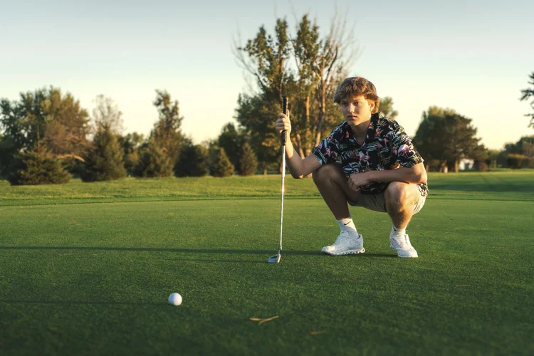 Senior holding a golf club on the course during his Wausa portrait session
