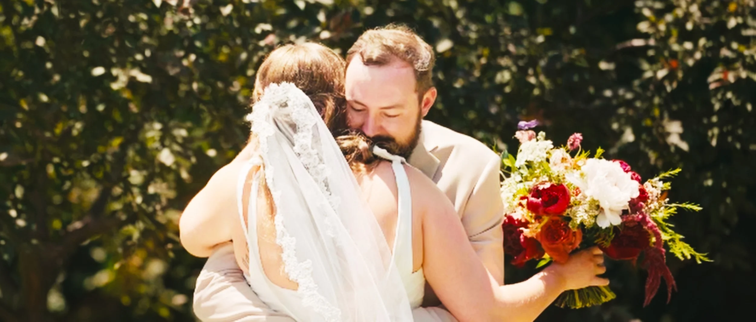 Bride and groom embracing during outdoor wedding at family home in Lincoln Nebraska with bouquet