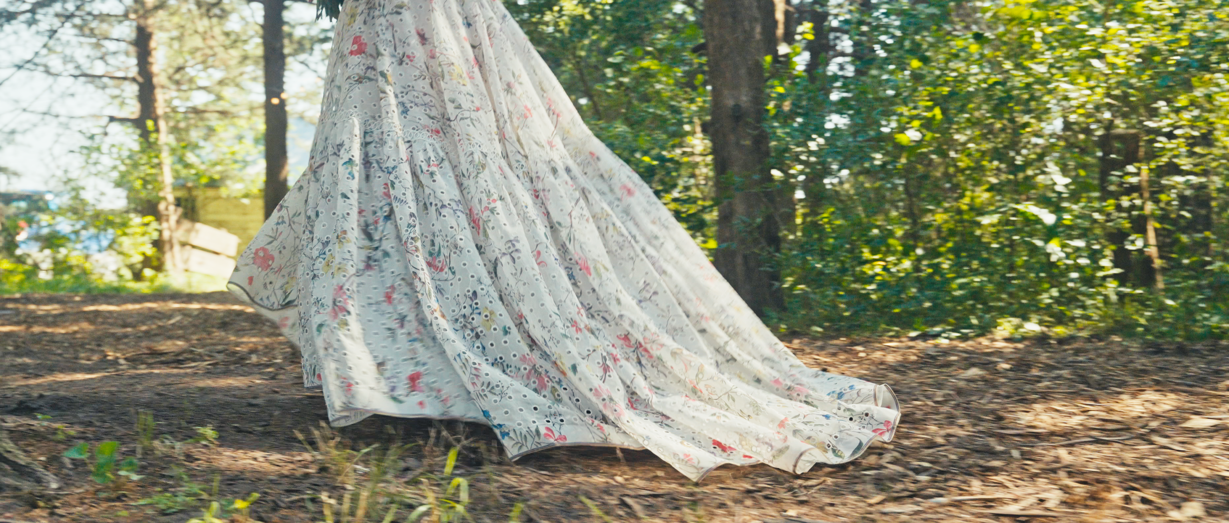 Bride’s Floral Wedding Dress Flowing Along Forest Ceremony Aisle