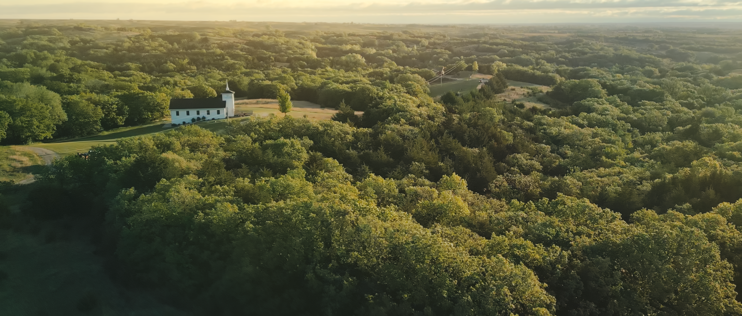 Aerial view of Prairie Hope Chapel surrounded by rolling countryside near O’Neill, Nebraska during golden hour
