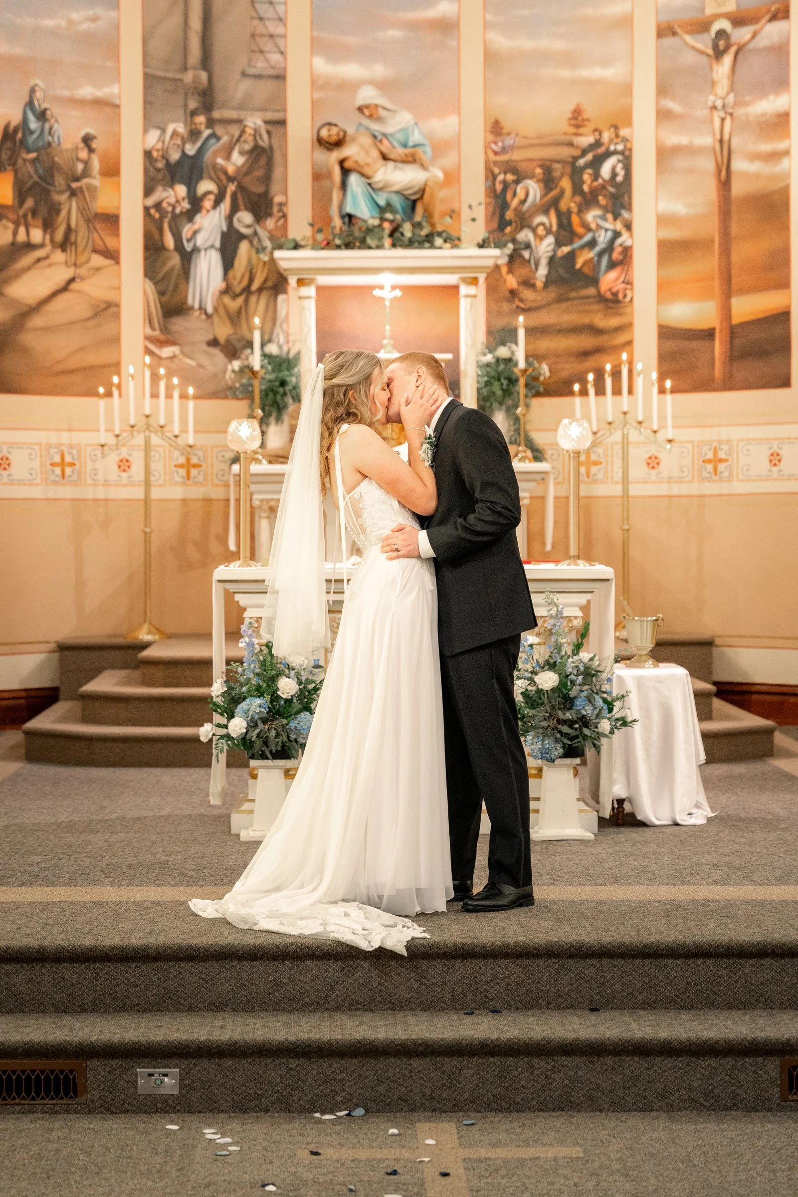 Bride and groom kissing in front of the altar in a Northeast Nebraska Catholic church.