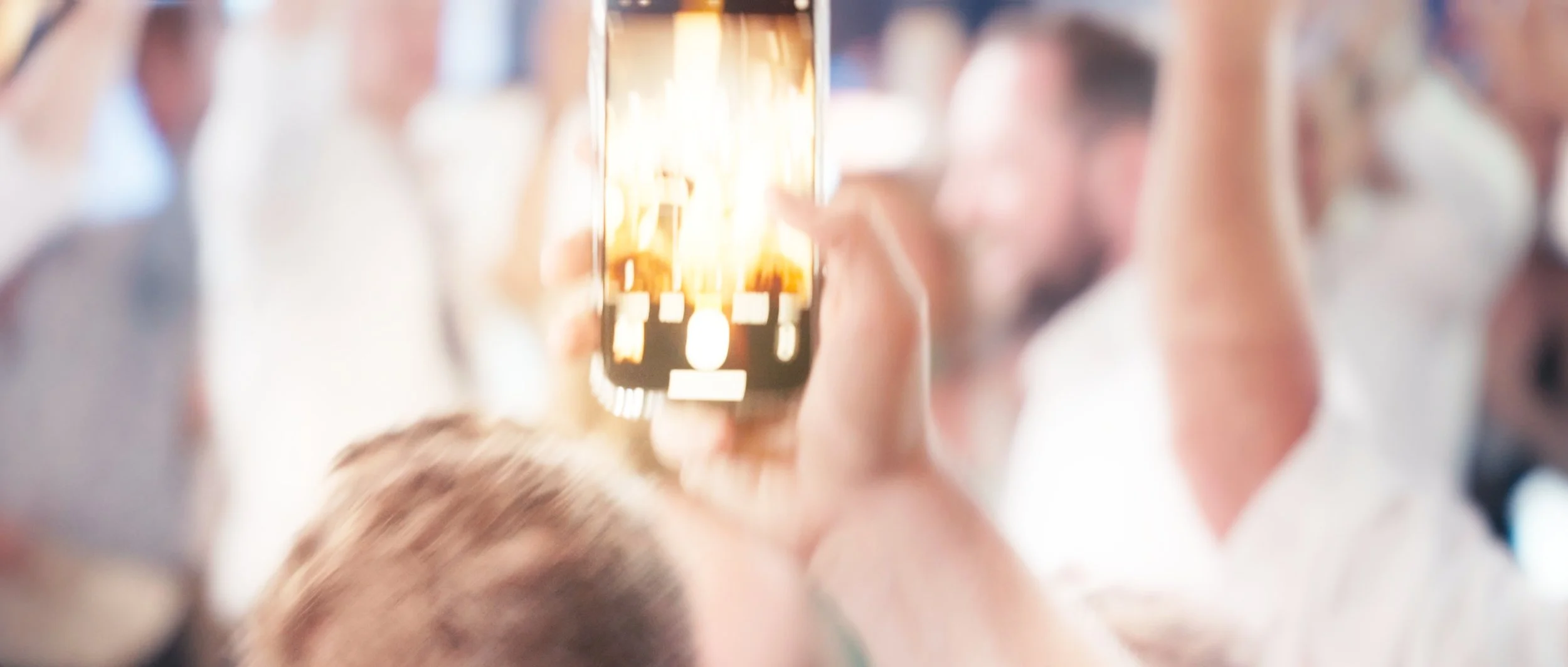 Guest recording wedding reception moment on phone at Lincoln Station Great Hall in Lincoln Nebraska