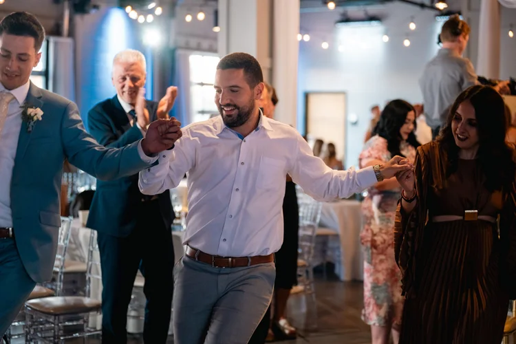 Wedding guests holding hands during a Greek dance at Grace and Alex's Diamond Room reception.