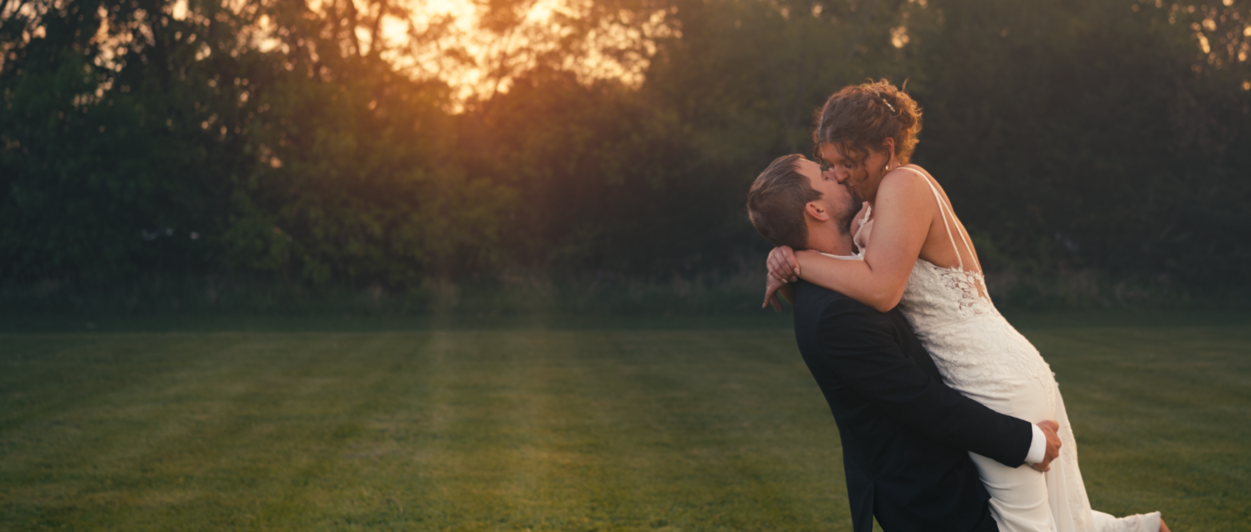 Bride and groom kissing at sunset outside the O’Neill Community Center in O’Neill, Nebraska