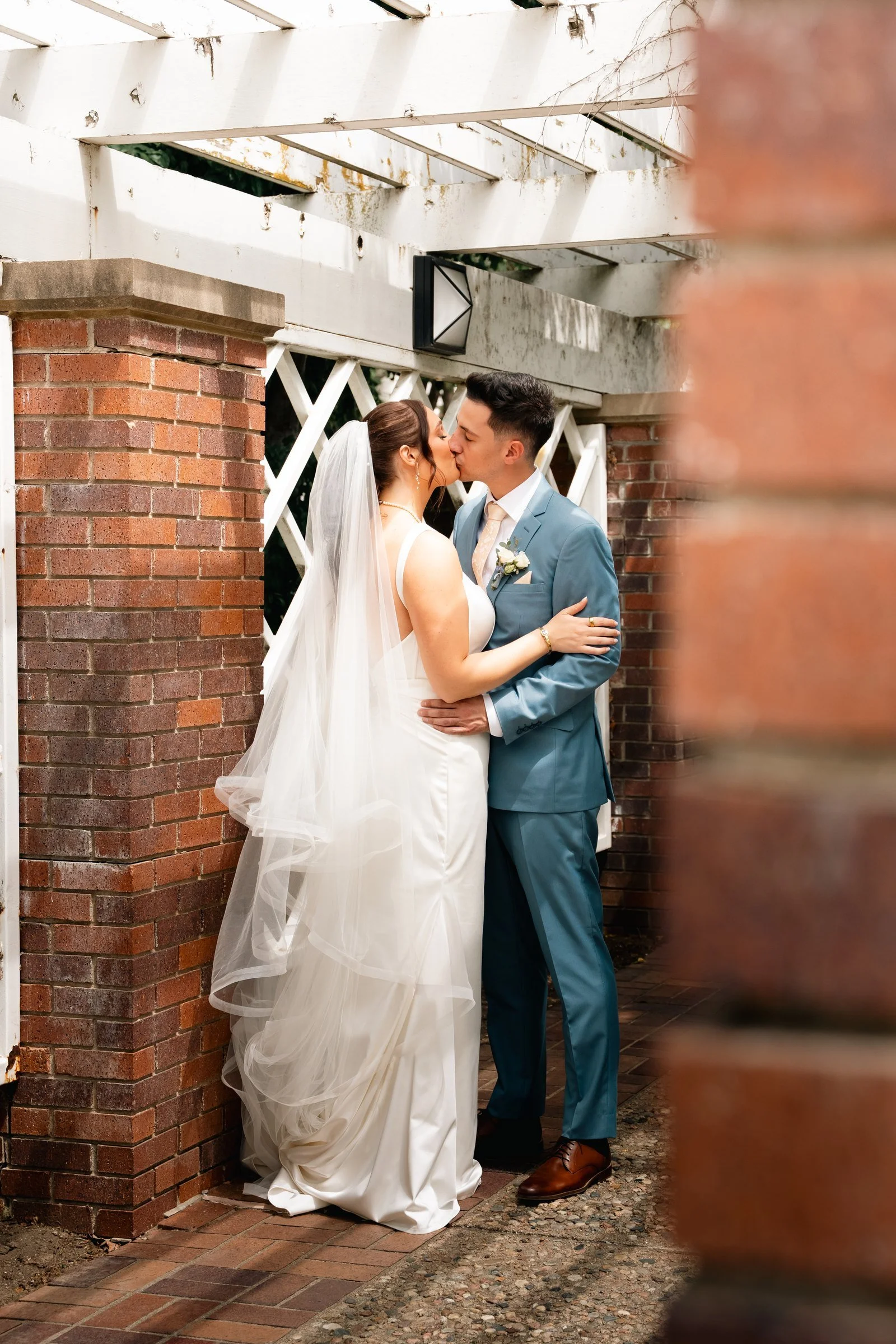 Grace and Alex standing together beside a brick arch in the Gerald Ford Birthsite gardens.
