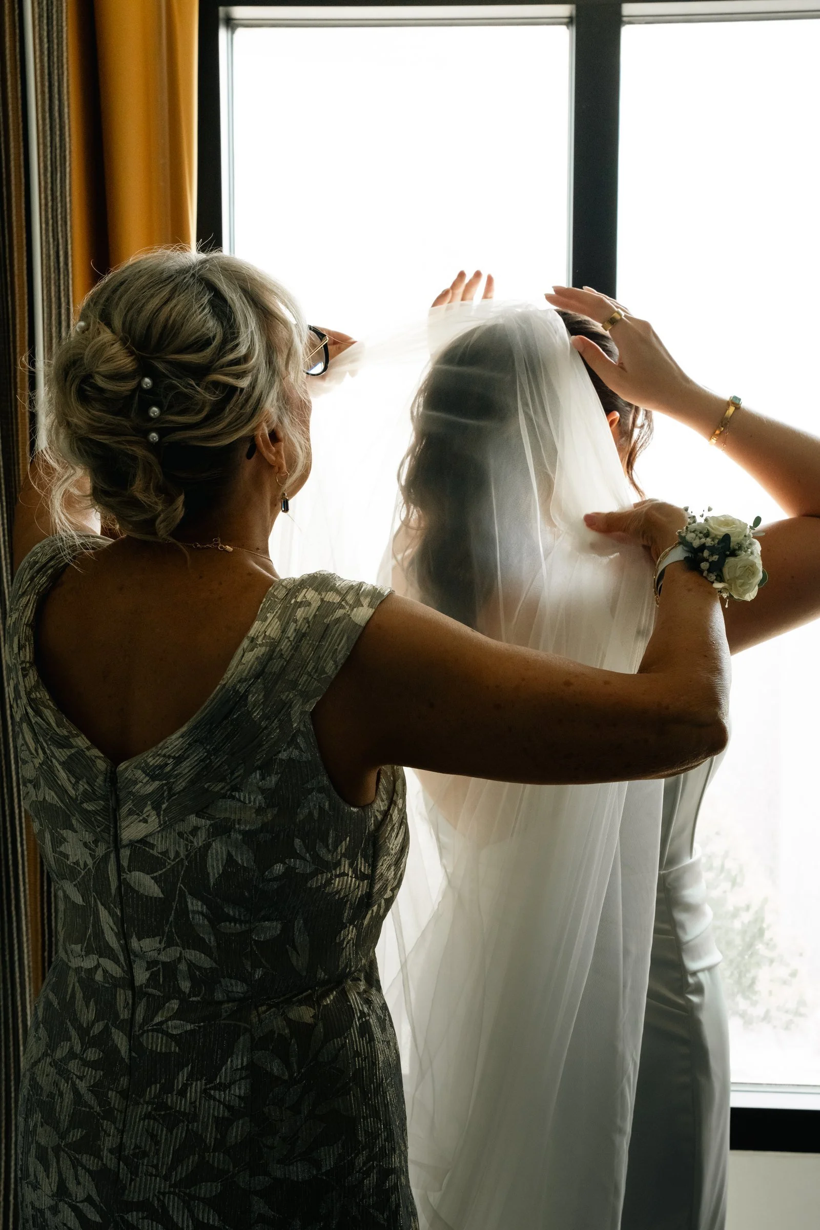 Grace adjusting her veil by the window while getting ready at the Hilton Omaha.