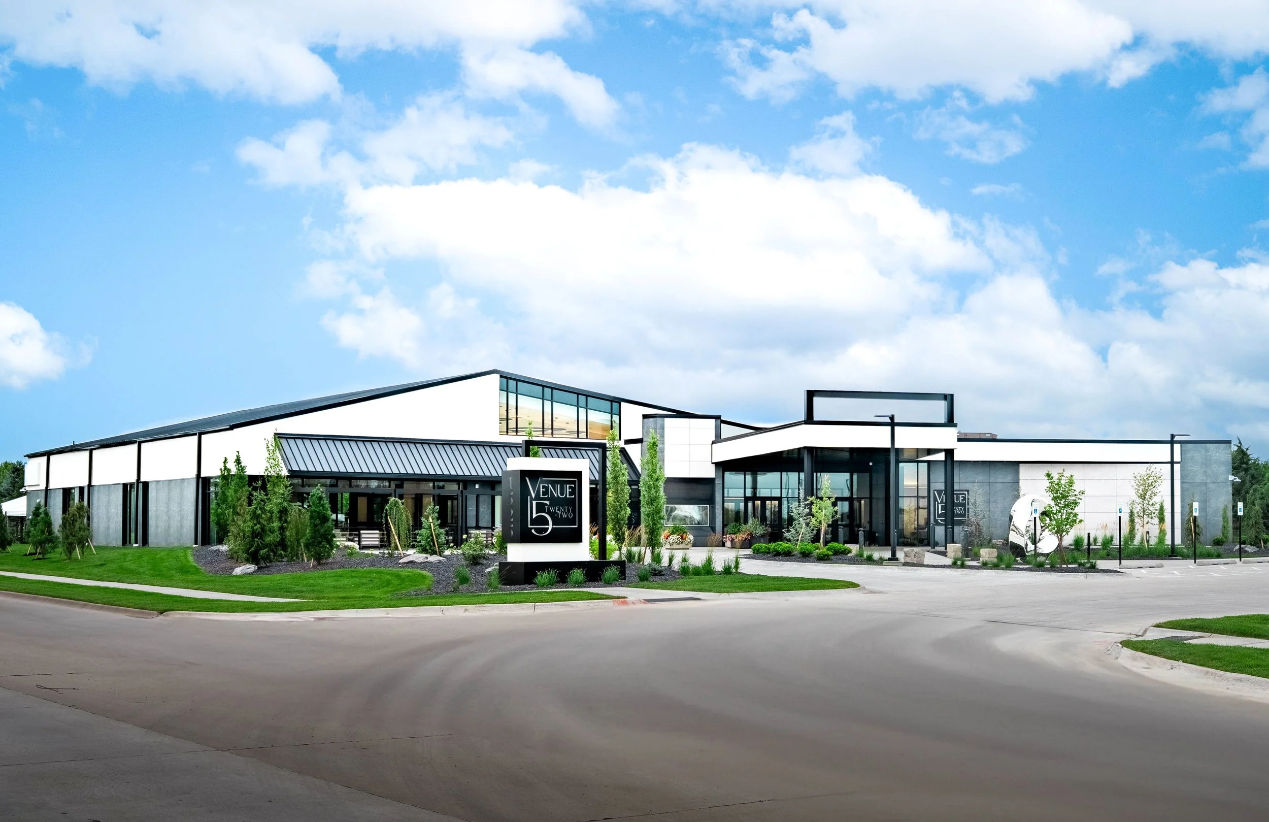 Modern commercial building with landscaped grounds and parking lot, sign reads 'Venue 55 Twenty Two'.