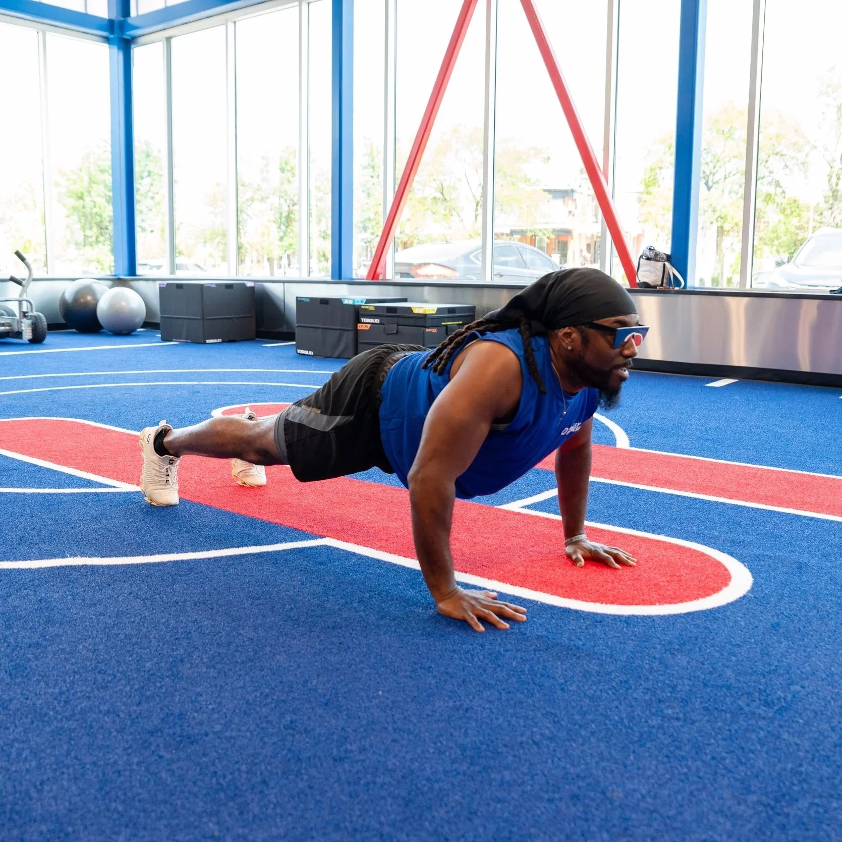 Gym member using the ATX Turf in their Blue Men's Philly Fitness® Muscle Tank