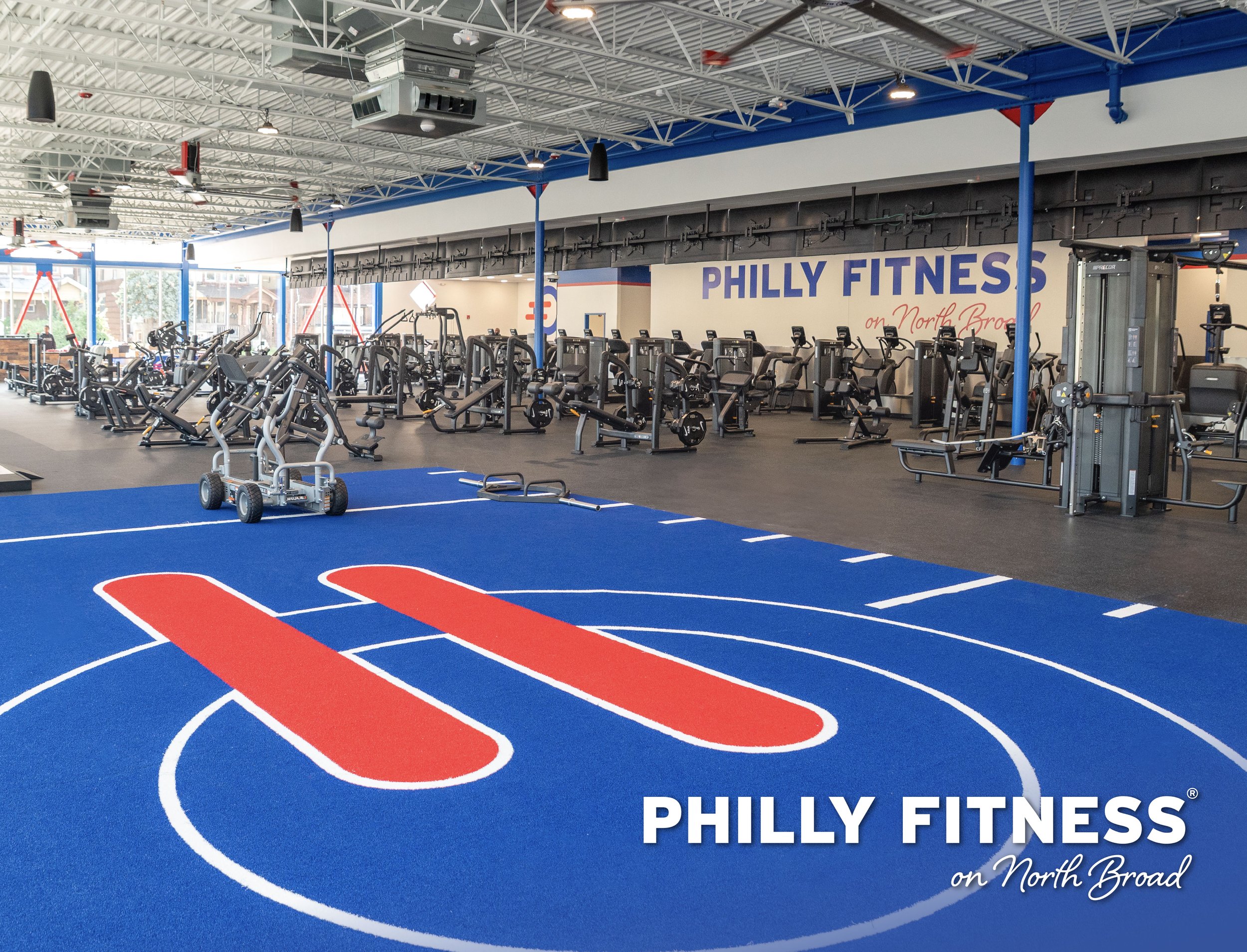 Interior of Philly Fitness gym with multiple weight equipment options and the Philly Fitness logo along the interior back wall