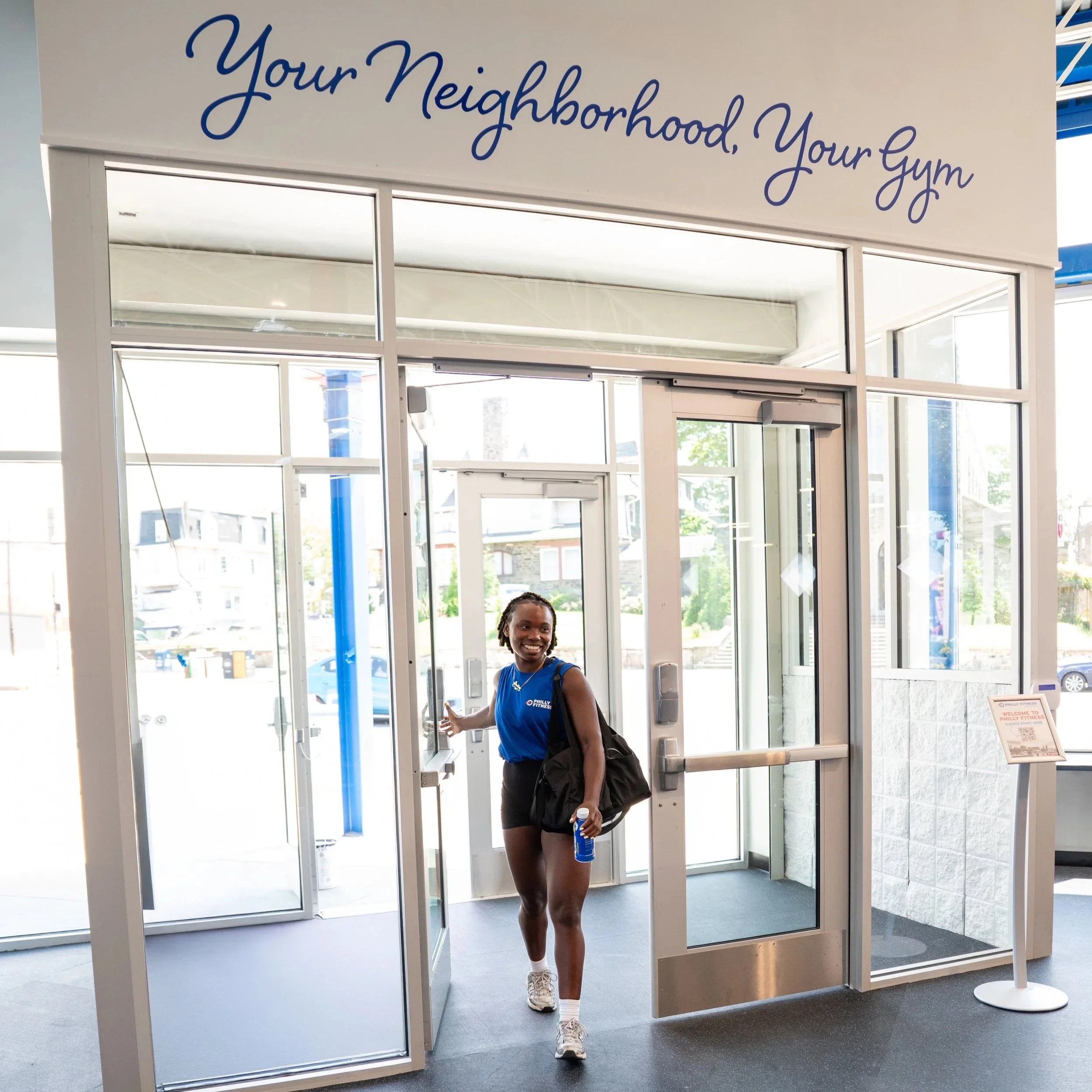 Philly Fitness® member walking in wearing a Blue Philly Fitness® Men's Muscle T-Shirt