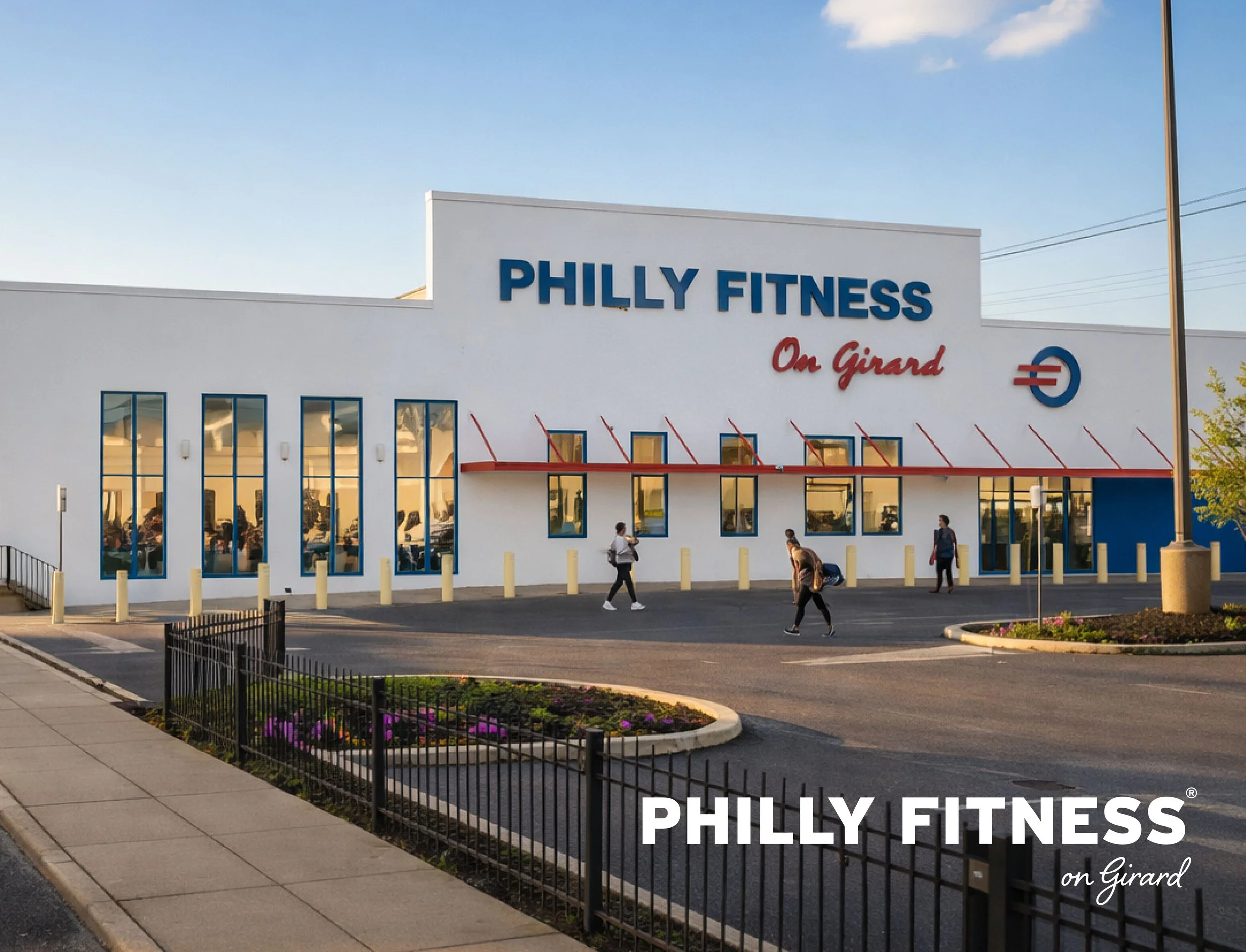 Exterior of a fitness center named Philly Fitness on Girard, with a white building, large blue and red signage, several tall windows, and a few people entering or walking near the entrance, during daytime.