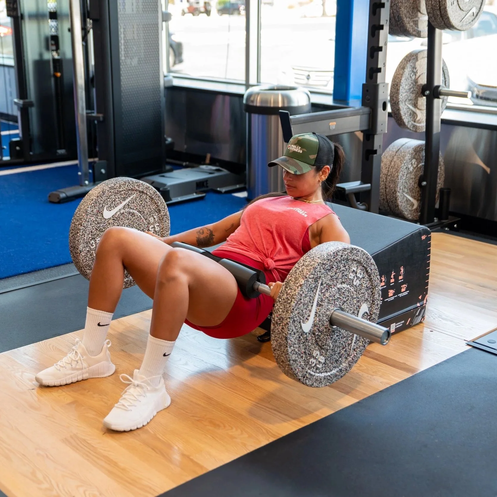 Gym member doing hip thrusts in a Red Philly Fitness® Women's Muscle T-Shirt