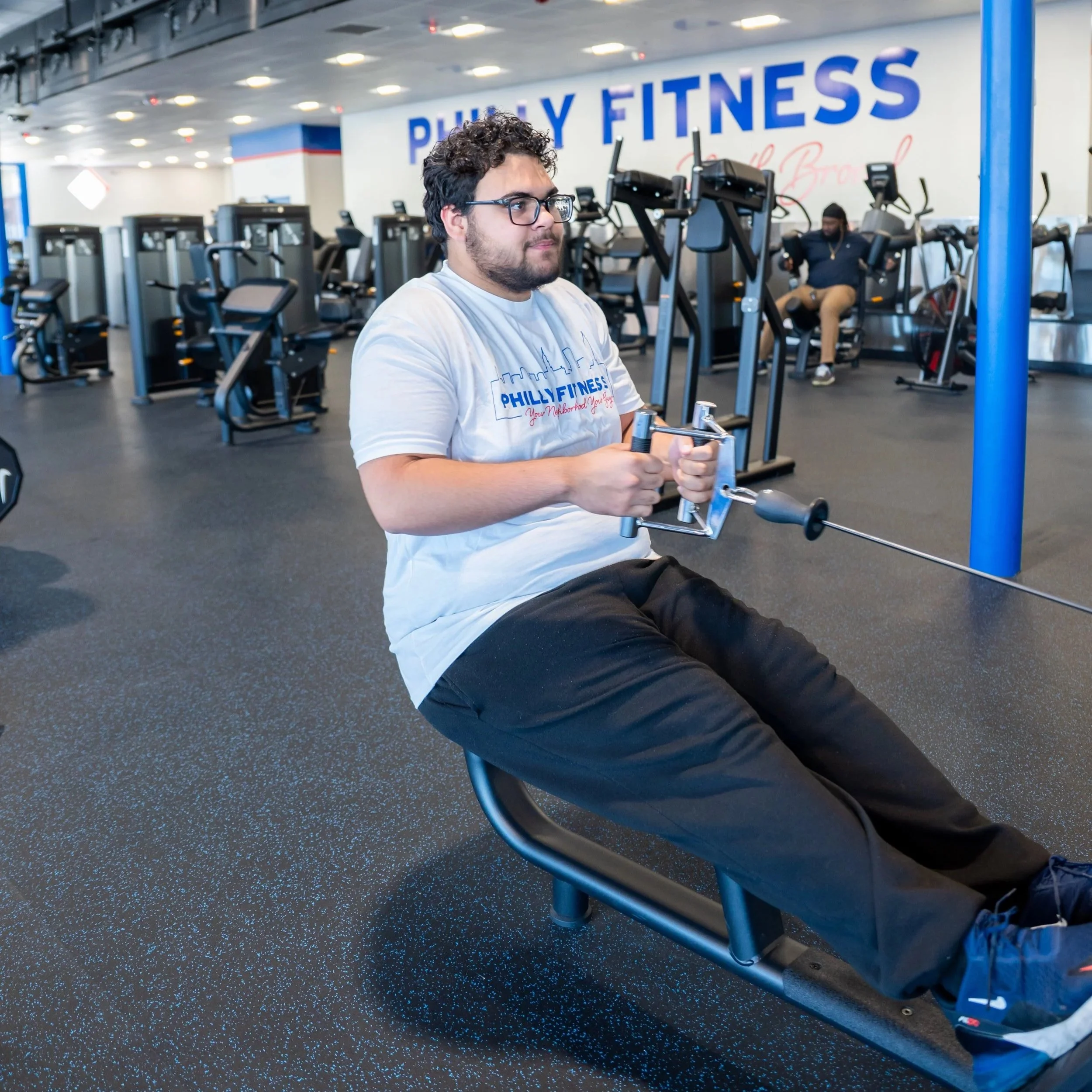 Philly Fitness® gym member on the stationary row cables in a Philly Fitness® White Skyline T-Shirt