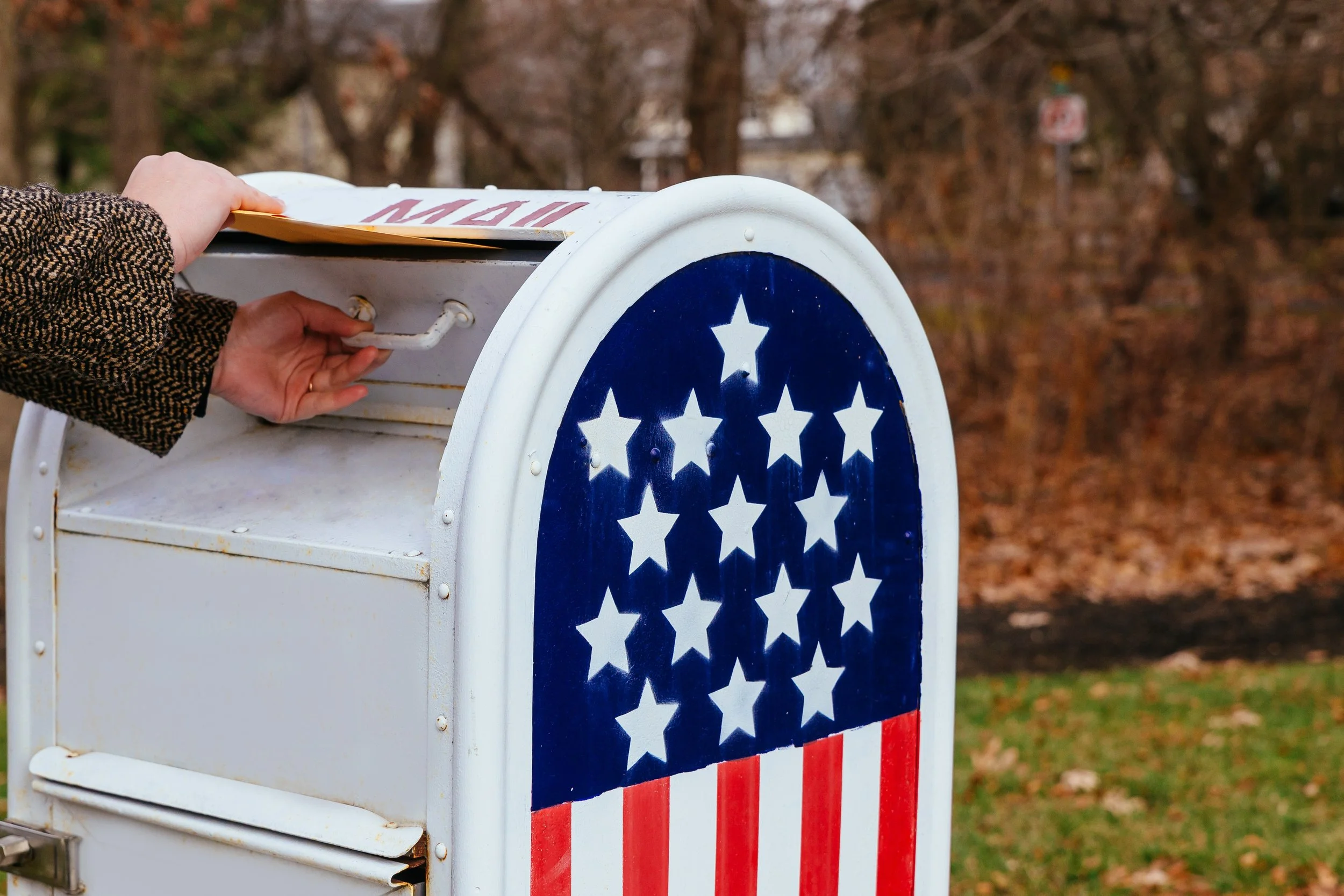 Person placing a mail ballot in a mailbox