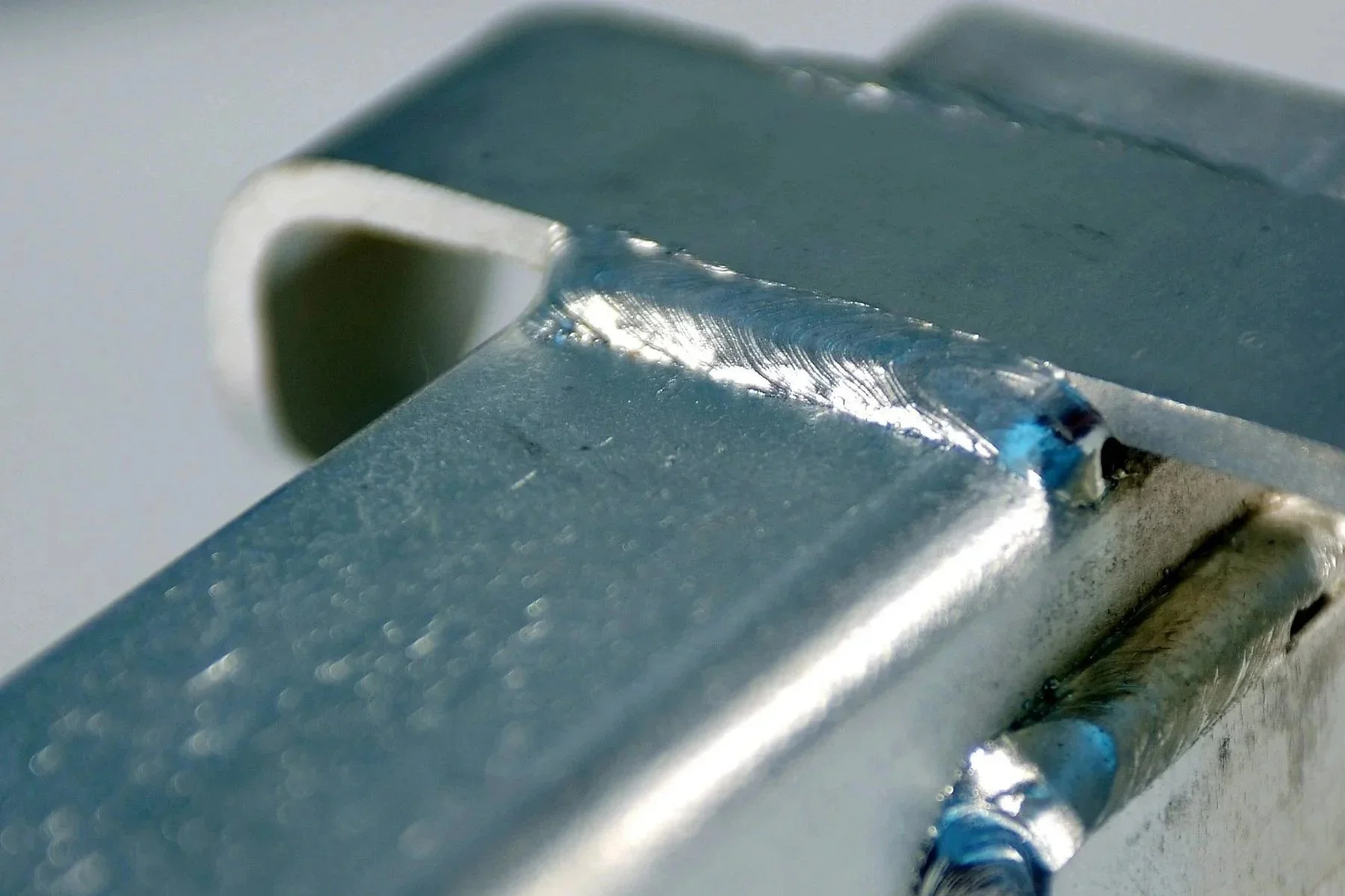 Close-up of TIG welds joining a metal bracket to square tubing