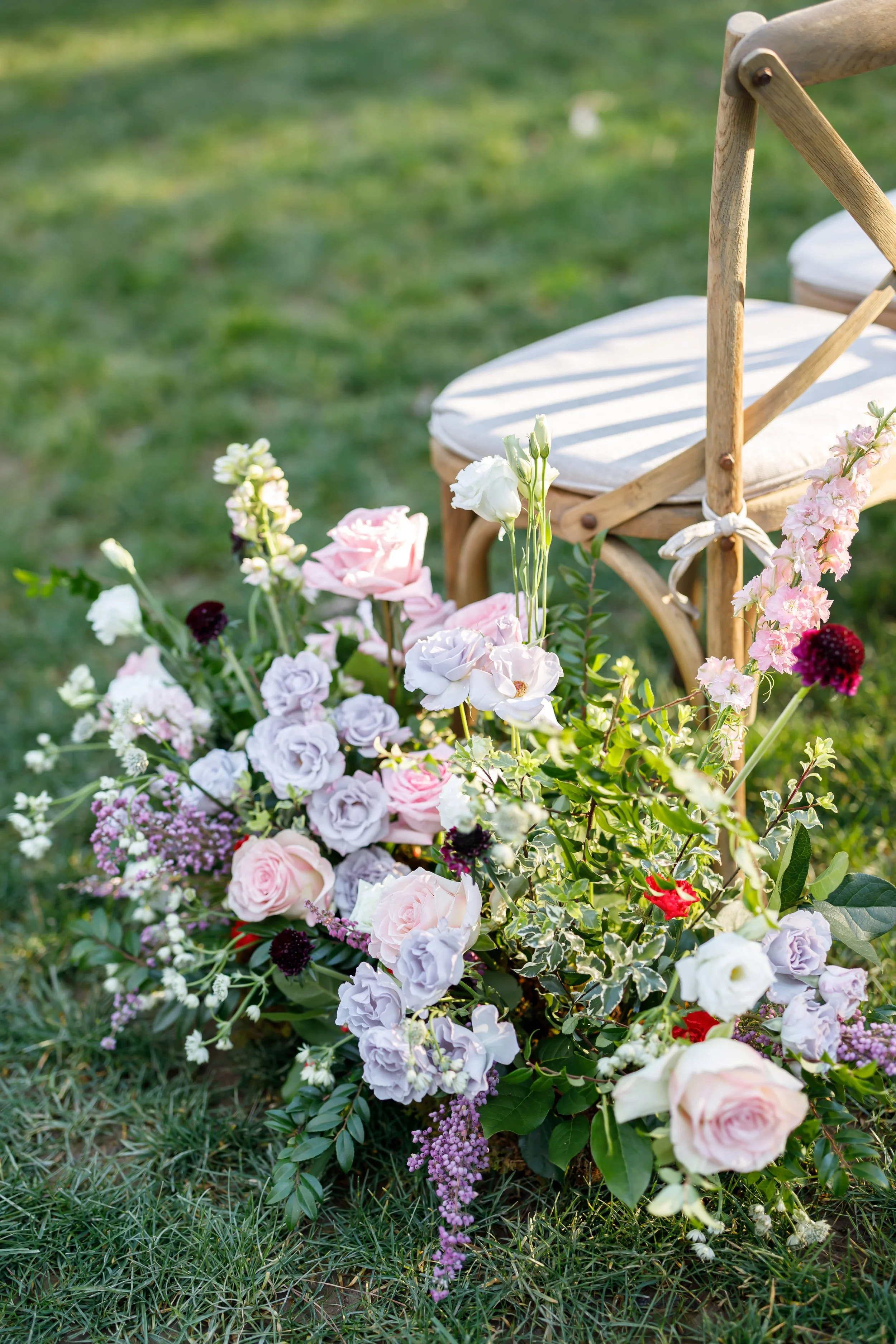 Flower arrangement on green grass with a wooden chair in the background