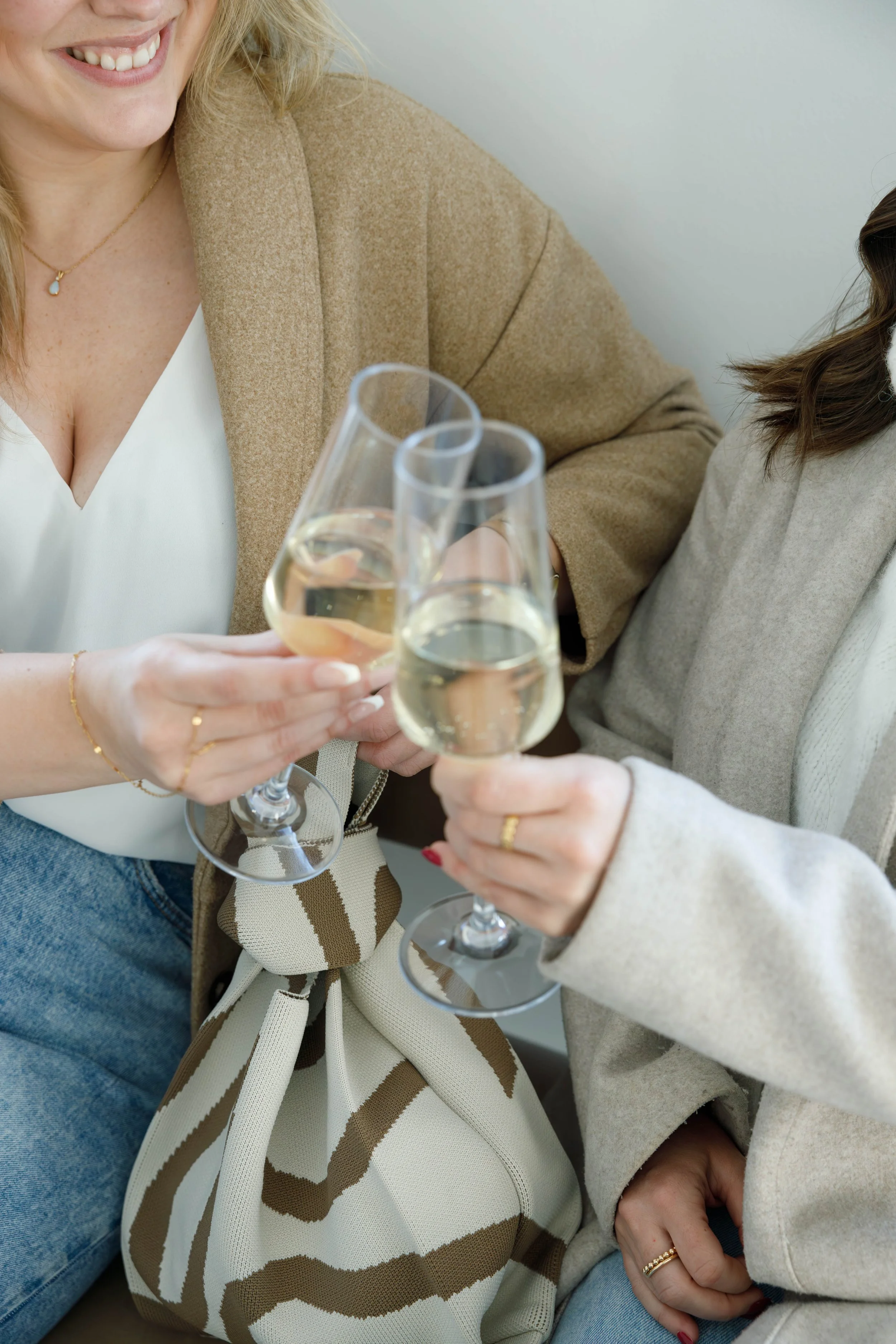 Two women clinking glasses of white wine.