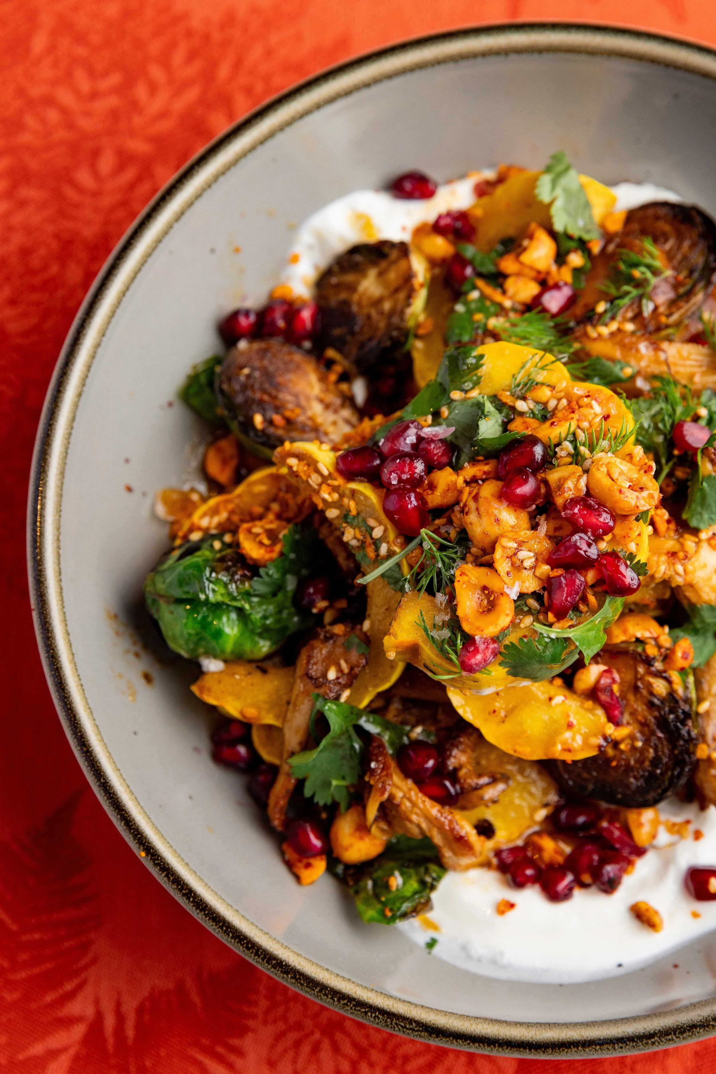 Roasted vegetables with pomegranate seeds and herbs on a plate.