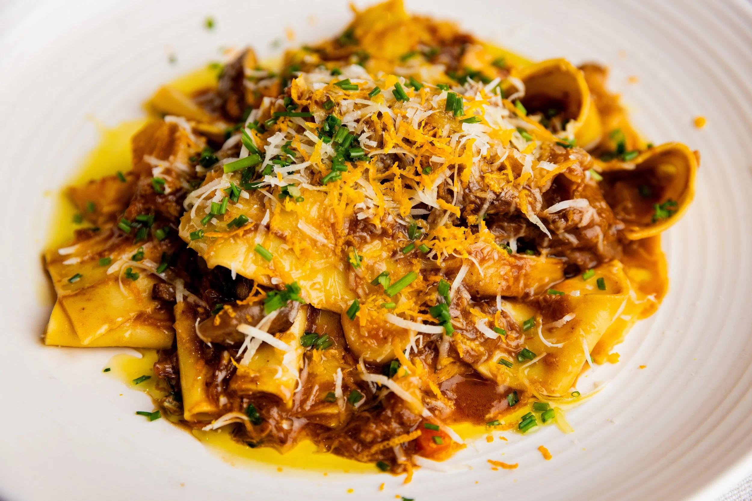 Plate of beef and mushroom ravioli topped with shredded cheese and chopped chives.