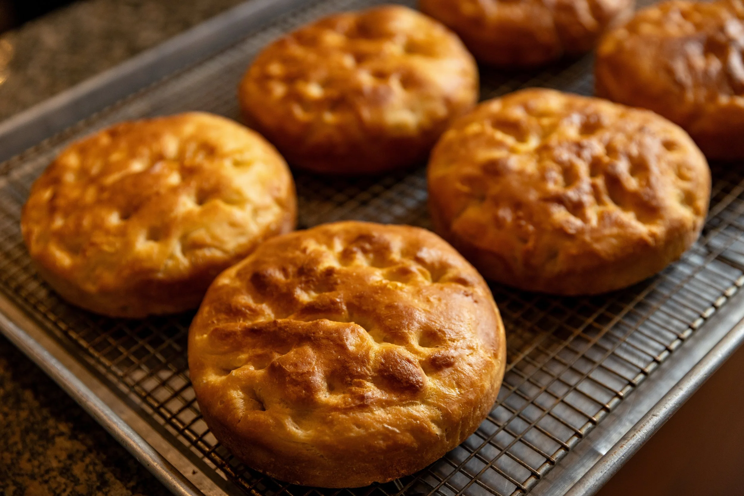 Golden brown baked bread rolls on a wire rack.