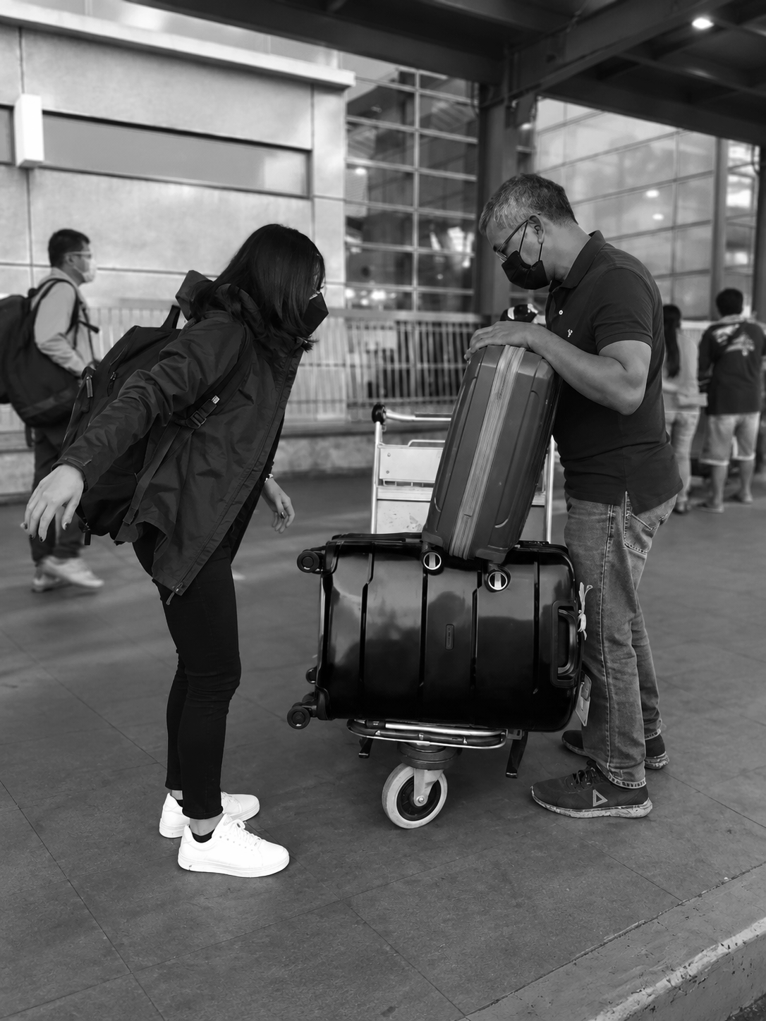 Father helping his adult child with luggage at the airport before departure