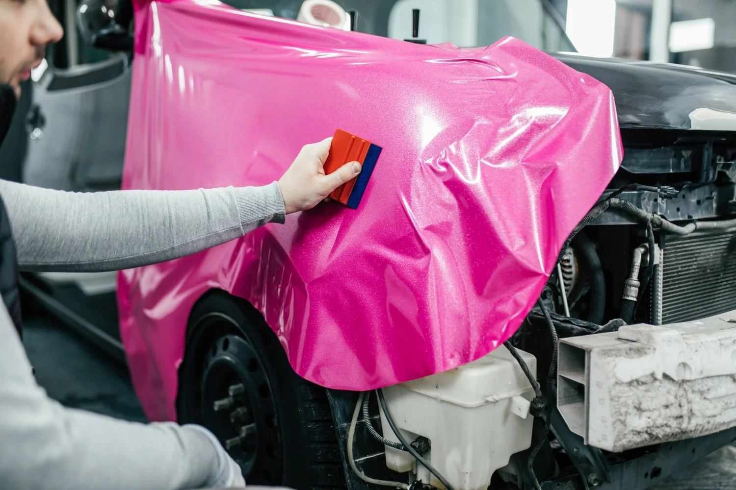 Pink wrap with metallic sparkle being applied to a vehicle
