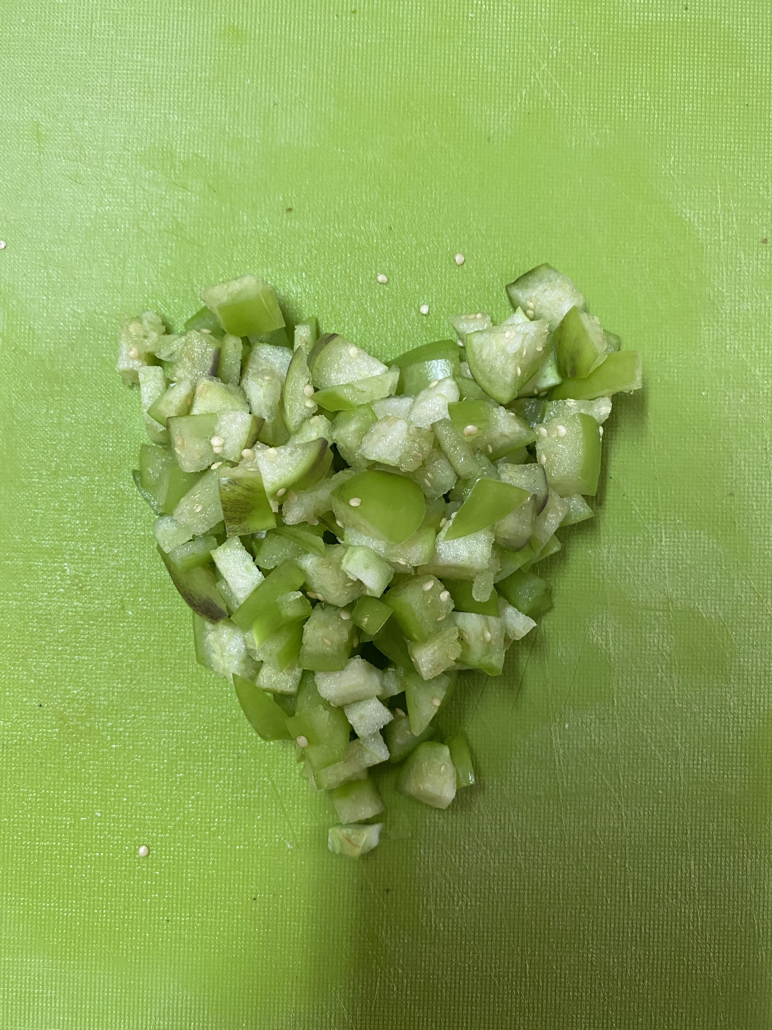 Chopped green vegetables, possibly zucchini or cucumber, on a green cutting board.