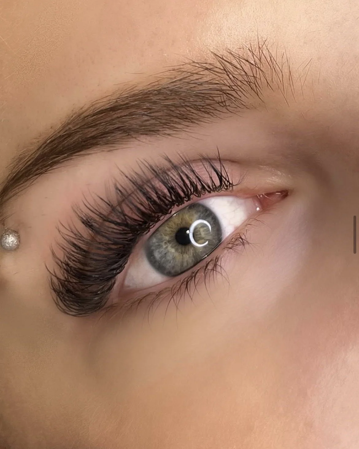Close-up of a woman's eye with long eyelashes and a grey-green iris.