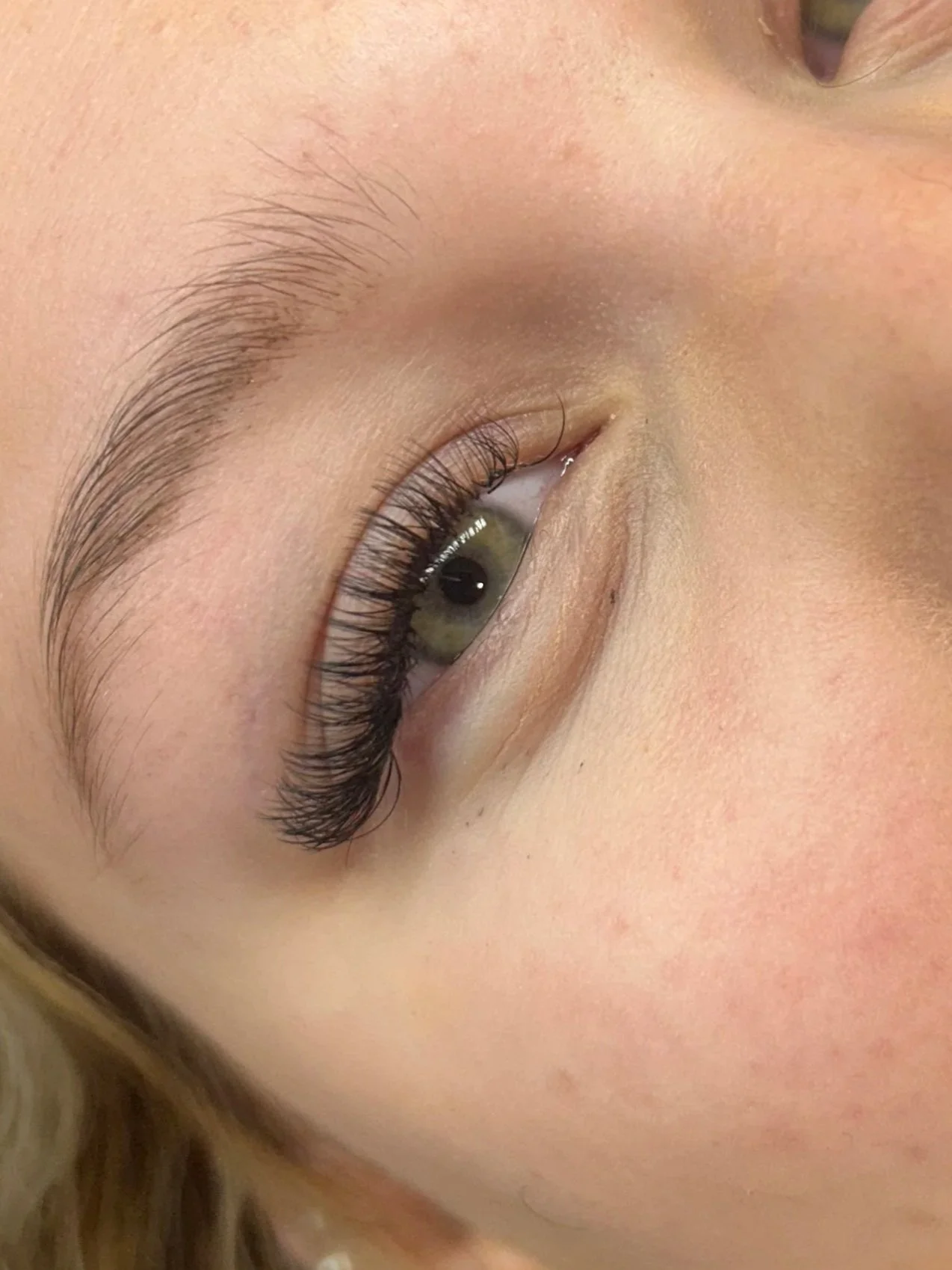 Modern house with wooden exterior, stone steps, and outdoor patio set against a mountainous landscape with snow-capped peaks.