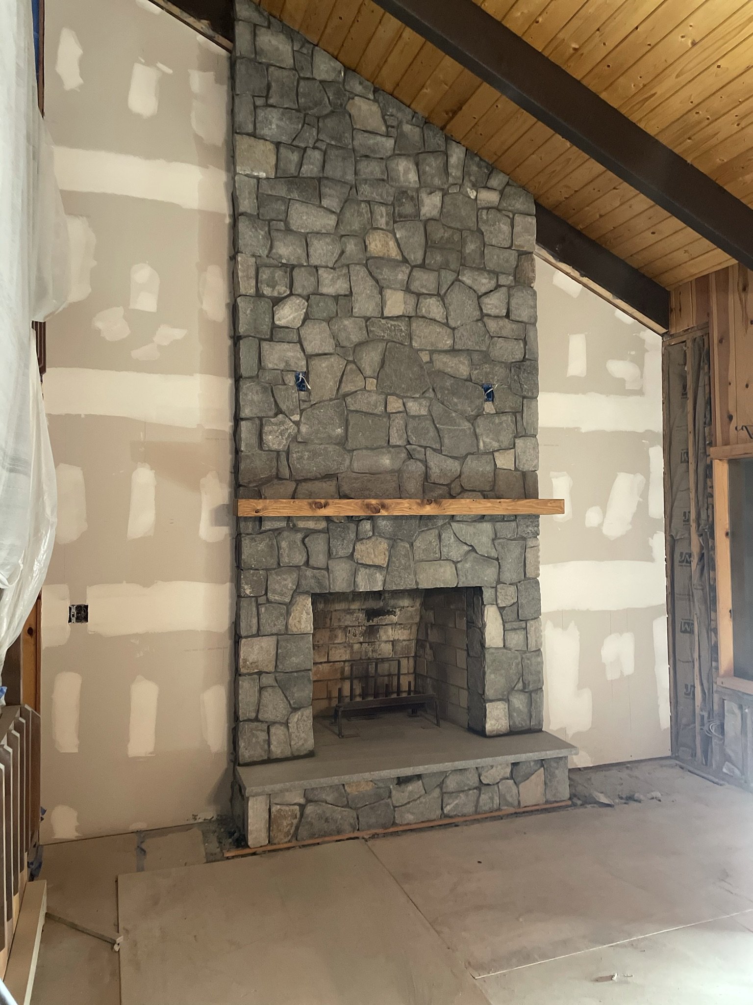 A granite stone fireplace is a striking focal point, in any space; a mason's work is typically done before the floor is installed or walls are painted