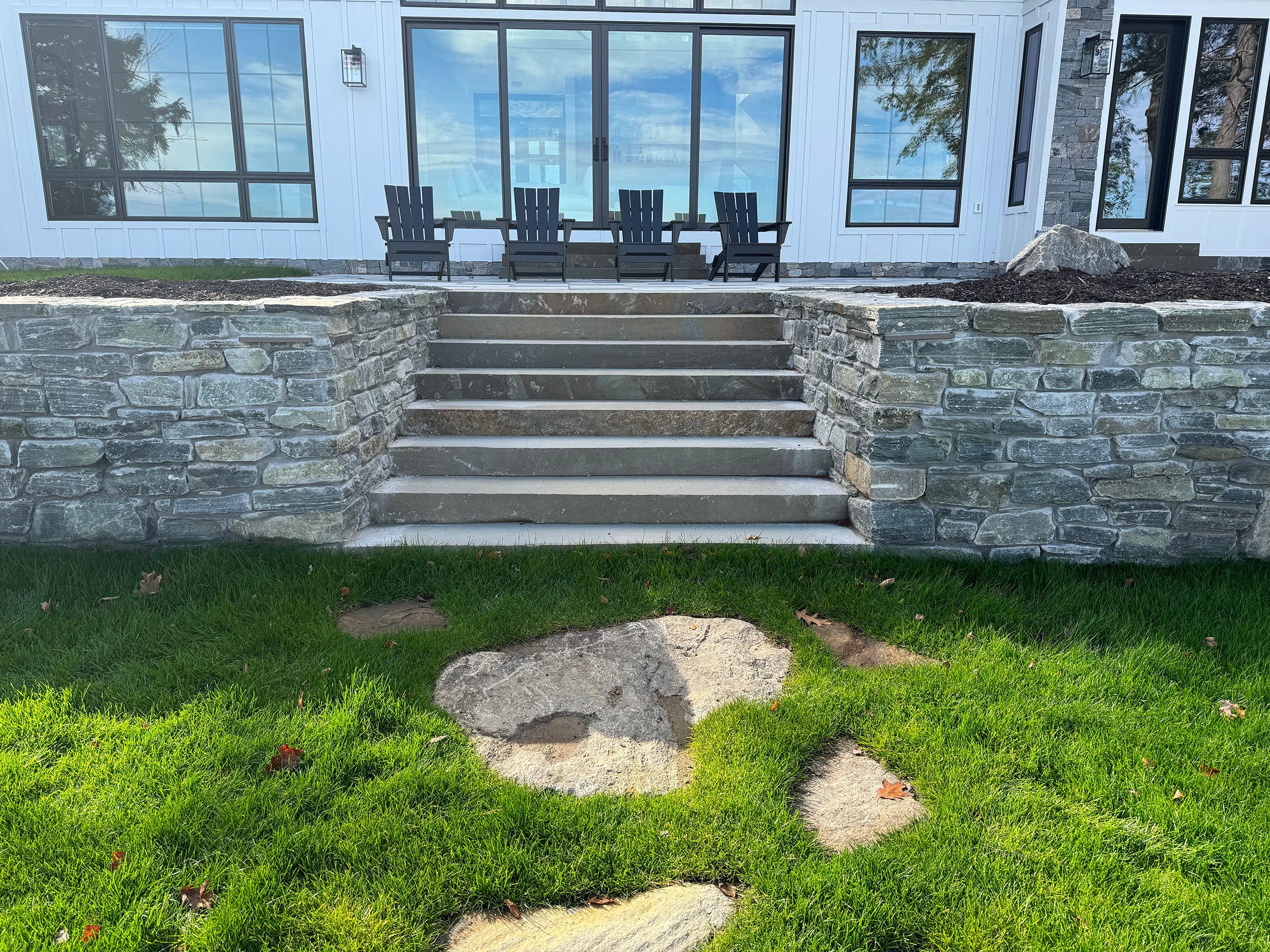 Stone steps and retaining wall welcome guests at a modern summer retreat in the Berkshires
