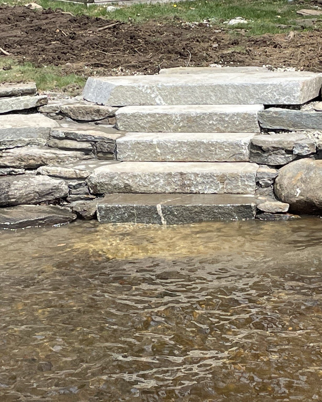 A rustic staircase descends gracefully towards calm waters, blending seamlessly with the natural surroundings
