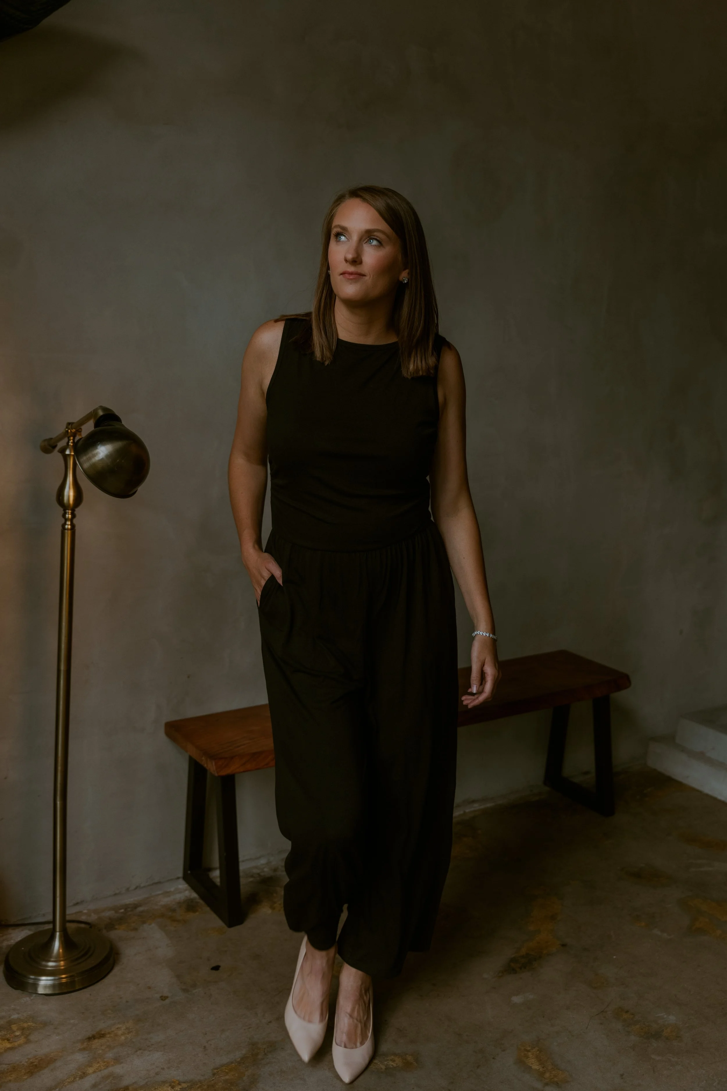Orlando branding portrait of woman in black outfit standing in studio with warm, moody lighting