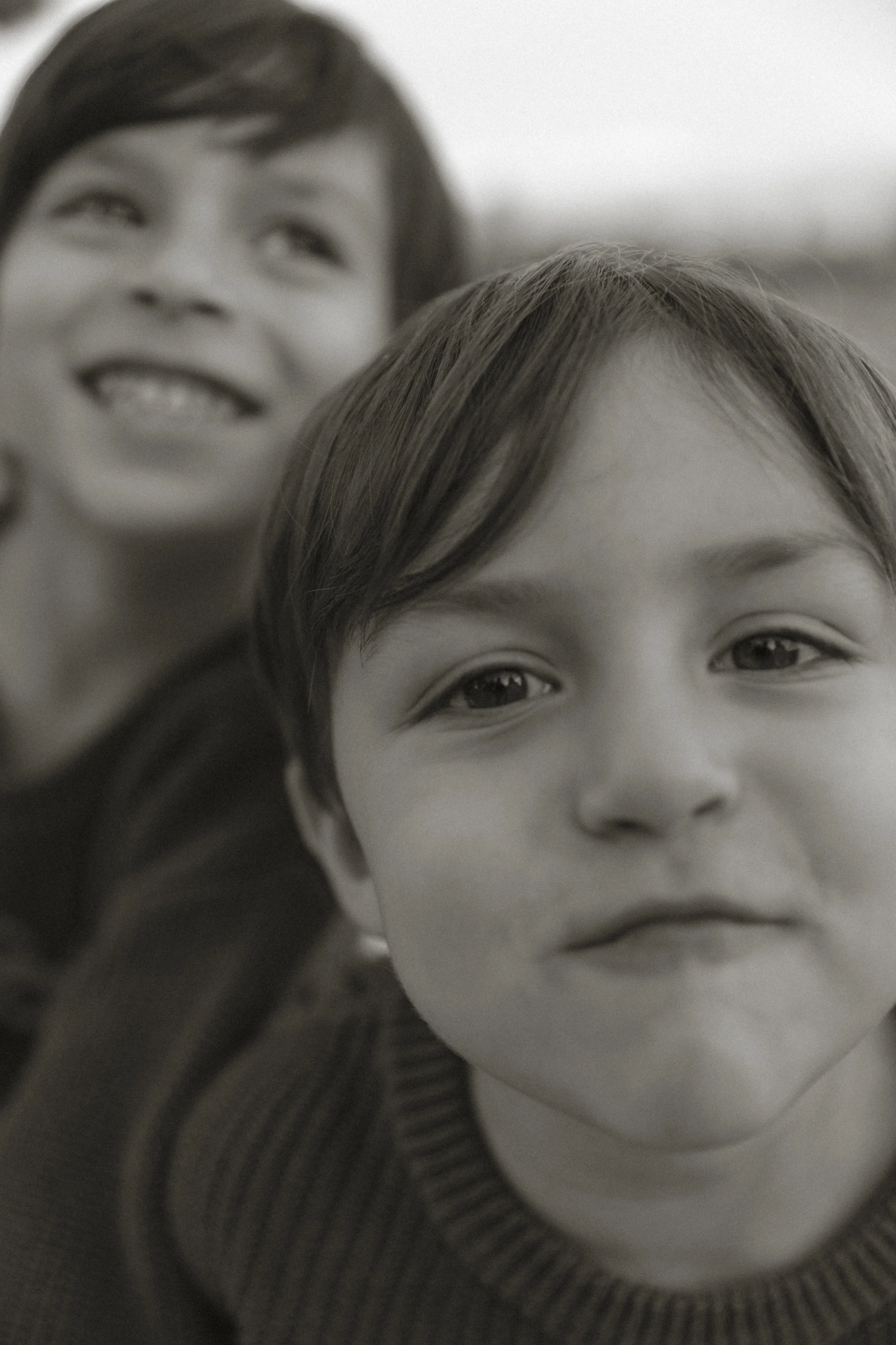Close-up of two young siblings smiling and looking toward the camera during a playful moment in a family photo session