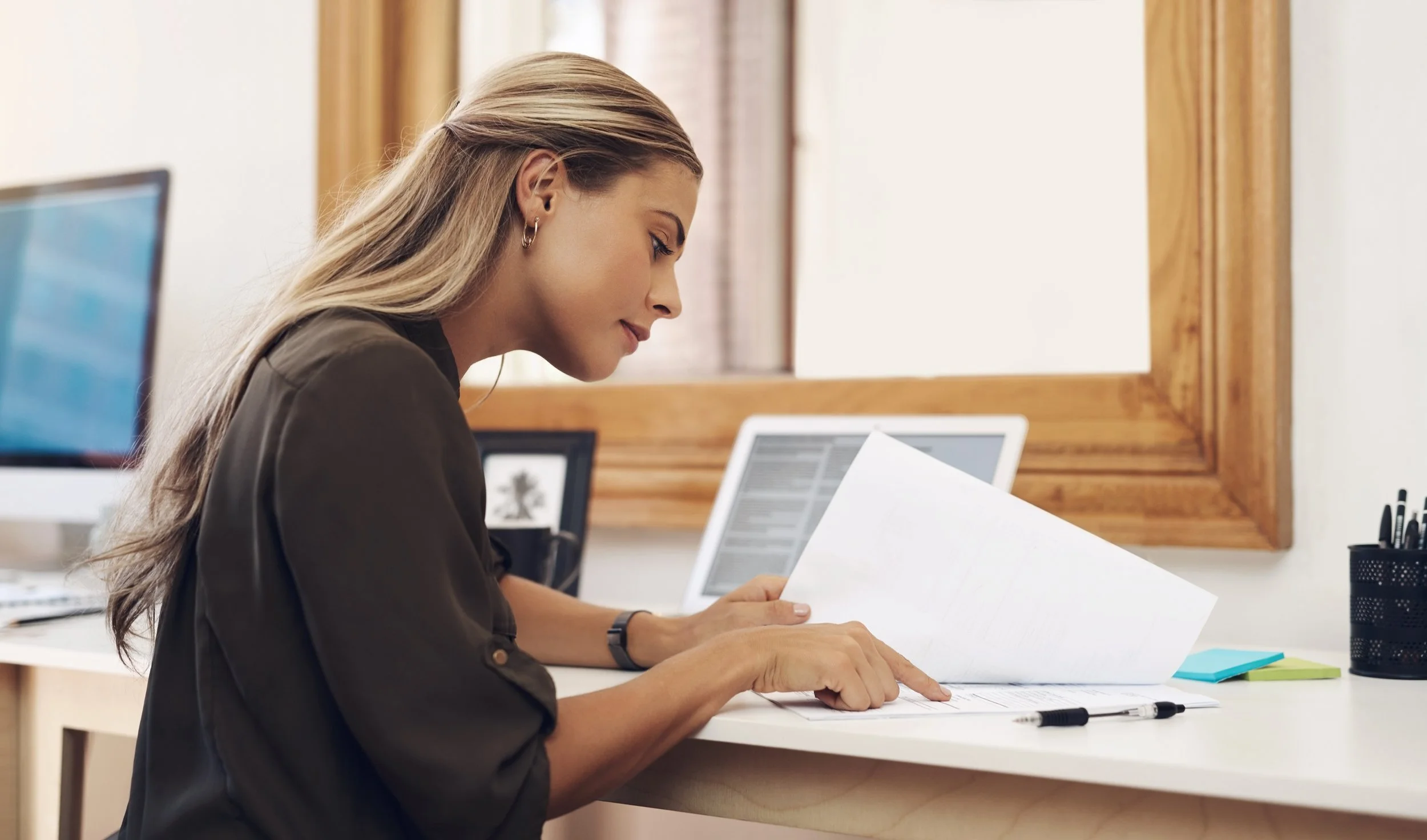 woman looking through paper work and sitting at a desk