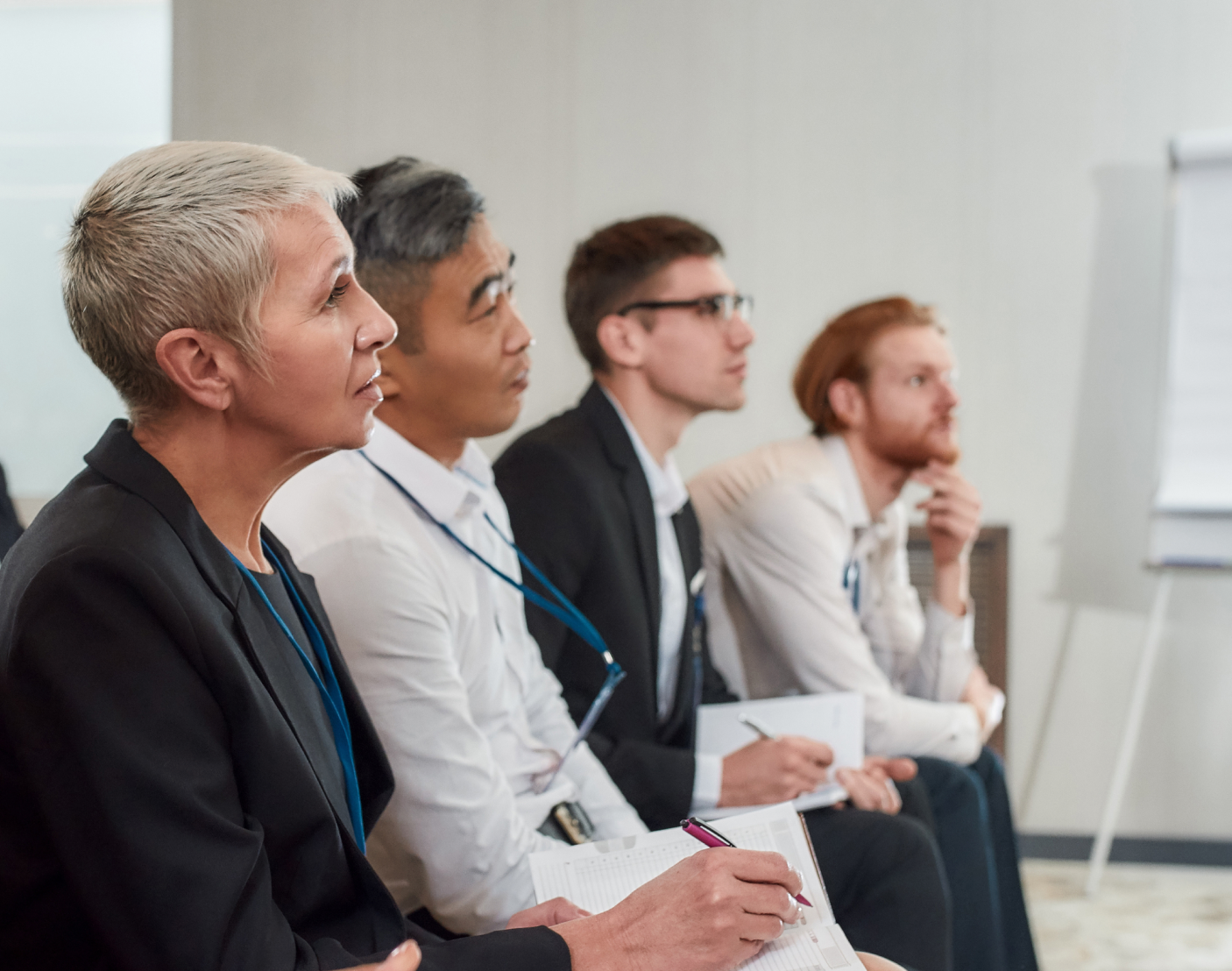 group of people sitting and watching a presenter while taking notes