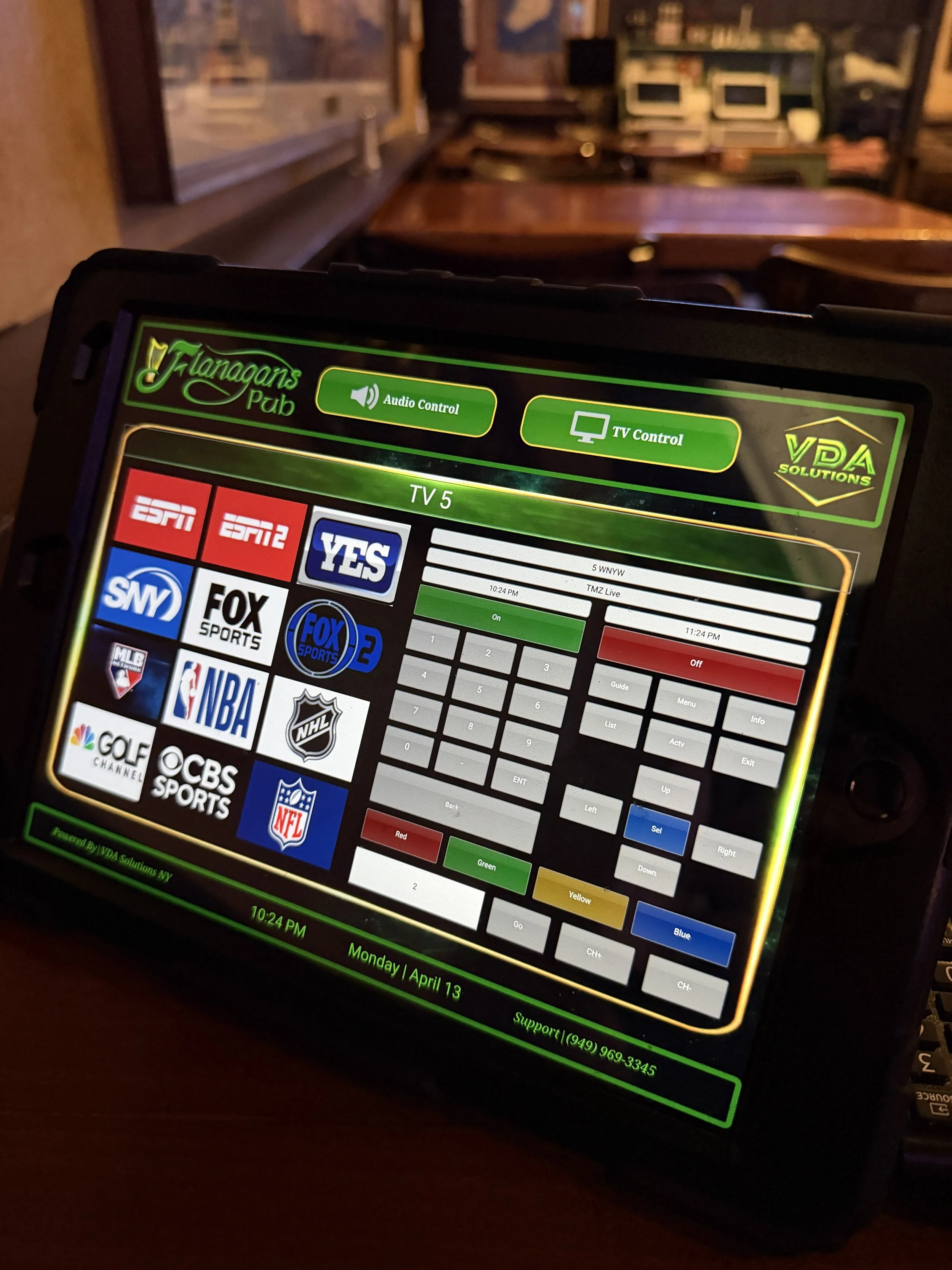 Touchscreen remote control displaying multiple sports and TV channels, including ESPN, YES, FOX, NBA, NHL, NFL, CBS Sports, and Golf Channel, with various menu options and color-coded buttons for channel selection.