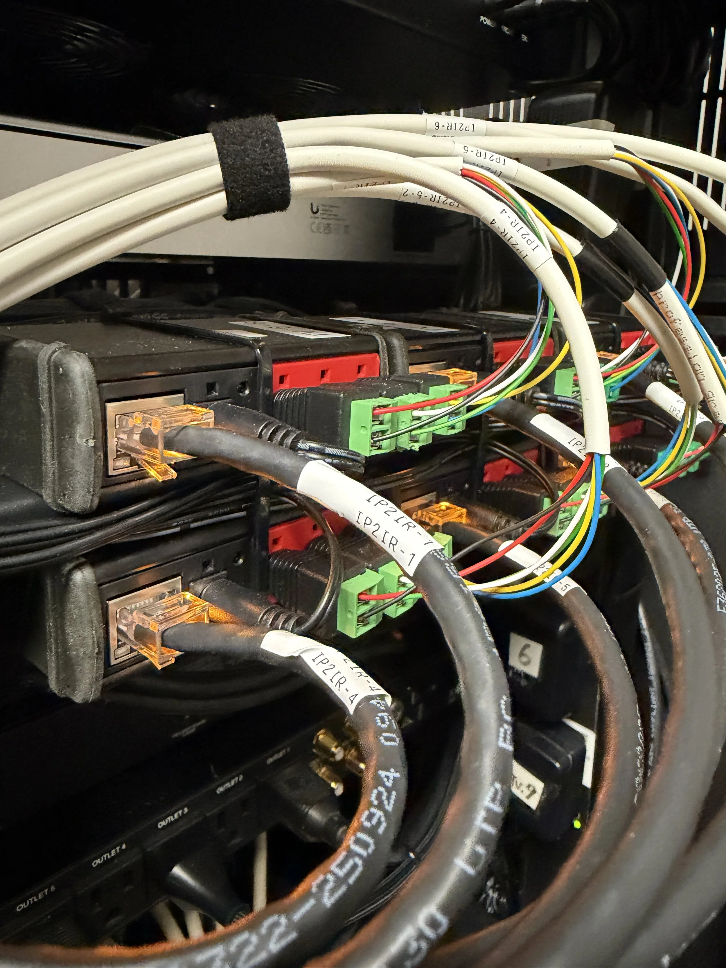 Close-up of electrical wiring and connections inside a machine, with various cables, connectors, and circuit boards. Global cache networking unifi TVS infrared