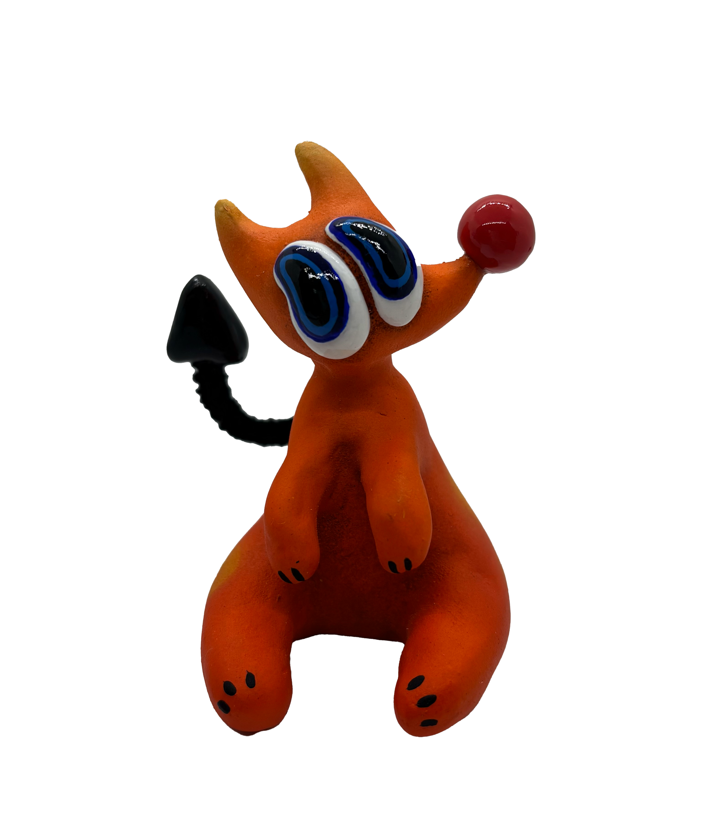 A small clay sculpture of an orange animal with large eyes, black spots, a red ball on its nose, and a black tail, standing on a flat surface.