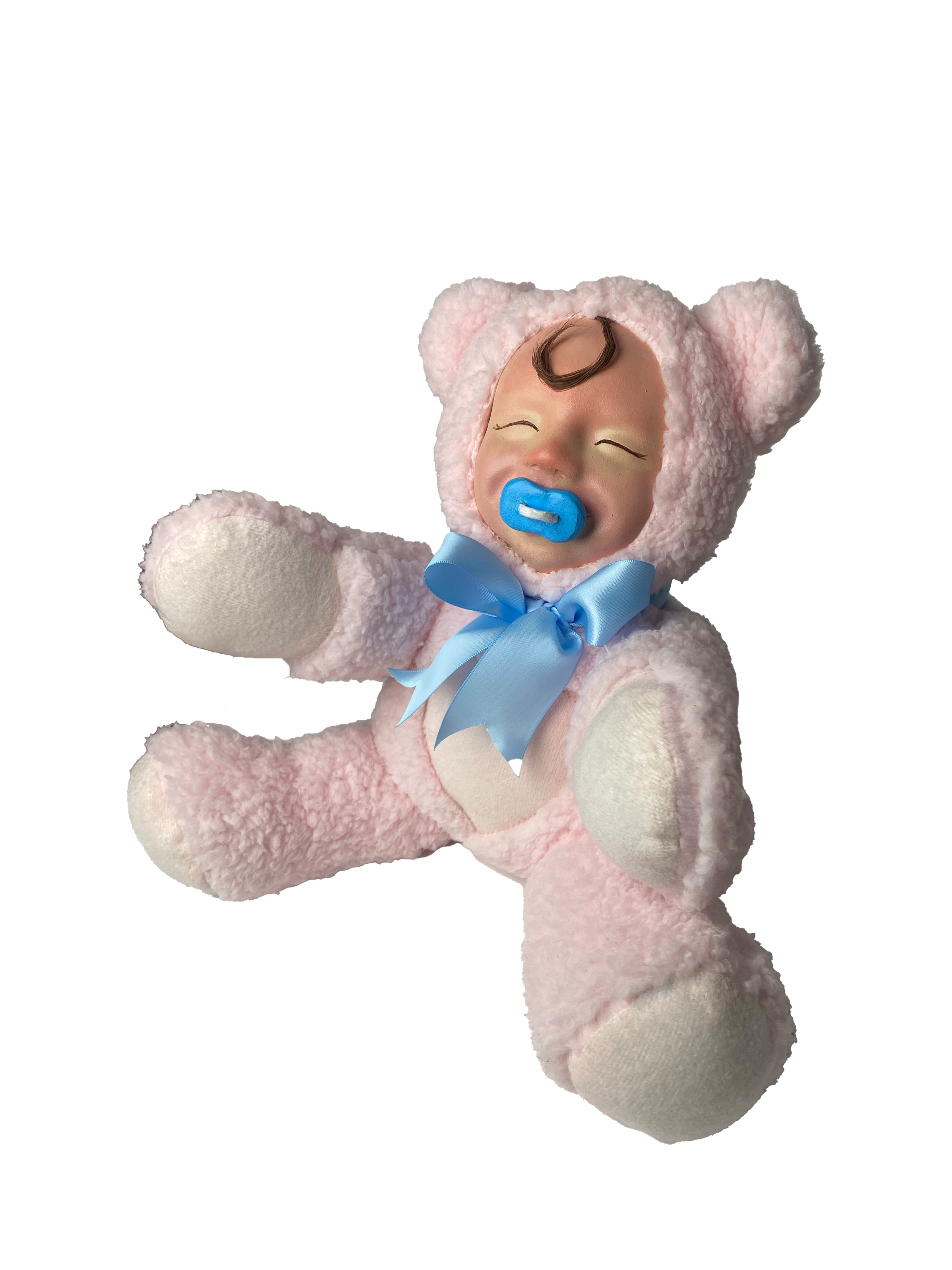 A plush doll dressed in a pink bear costume with a hood, blue ribbon, and pacifier, appearing to be a crying baby.