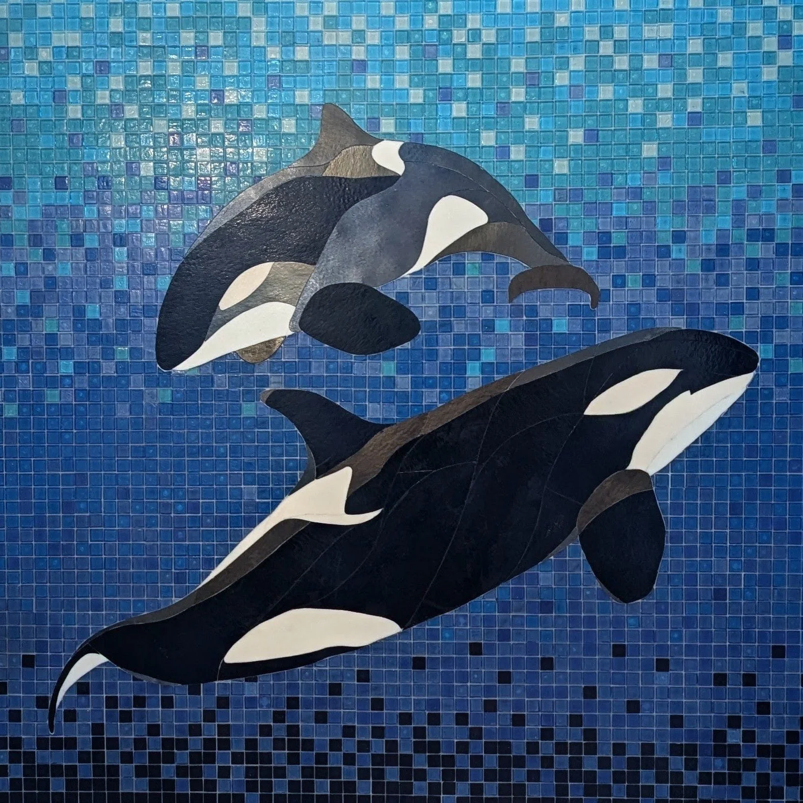 Decorative tile mosaic featuring killer whale or orca in black and white colors, set against a blue mosaic background.