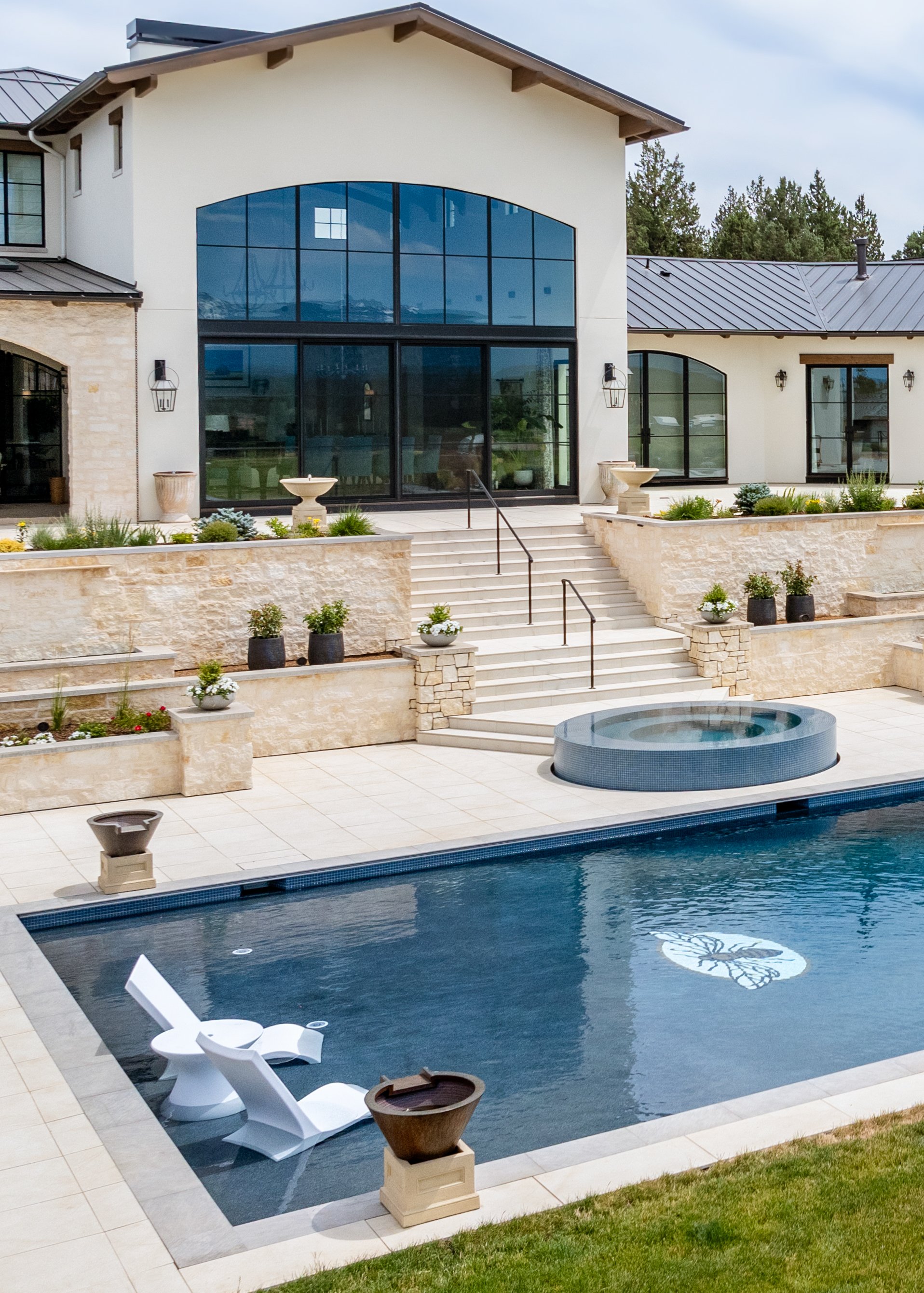 A backyard with a swimming pool, poolside lounge chairs, and a modern house with large windows and a patio area.