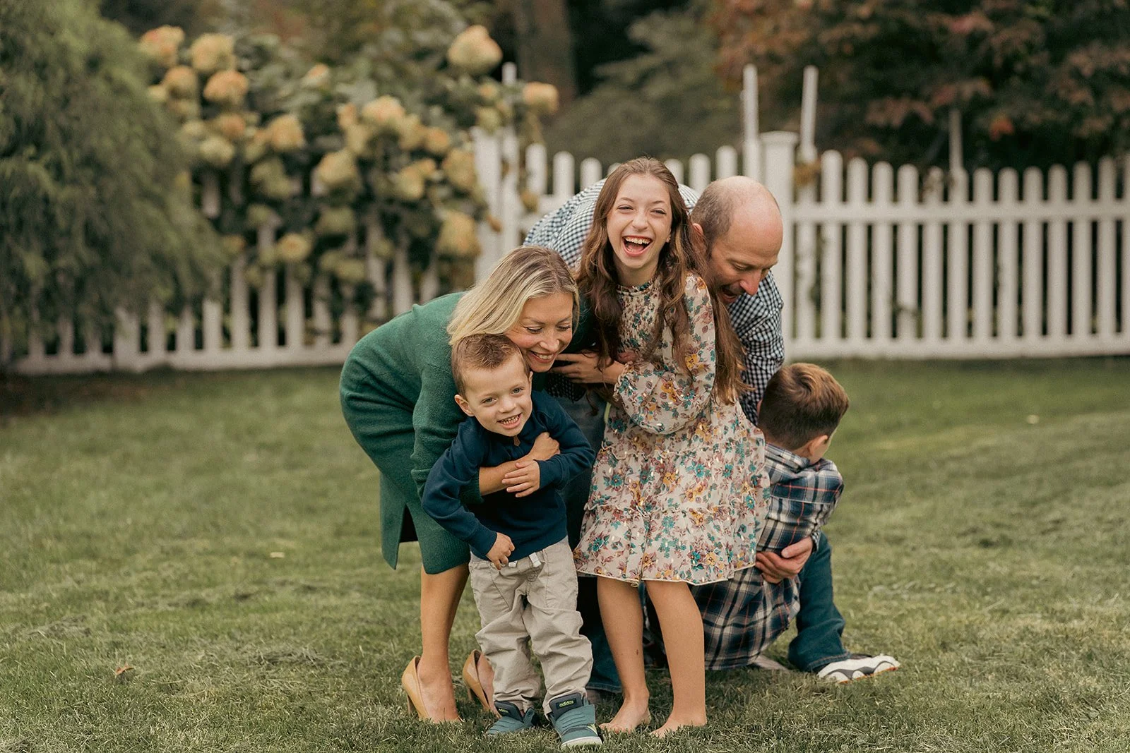 kids laughing while hugging their parents in their backyard