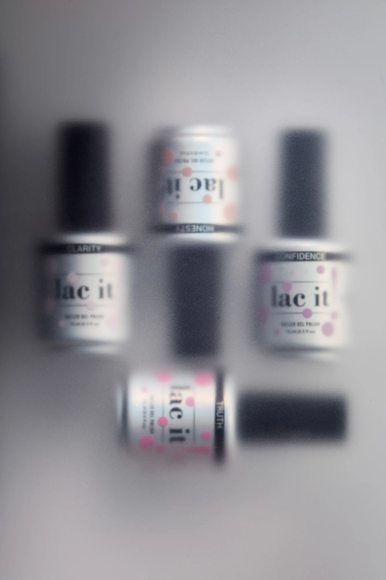 Four bottles of Lac It skincare products viewed through a frosted glass surface.
